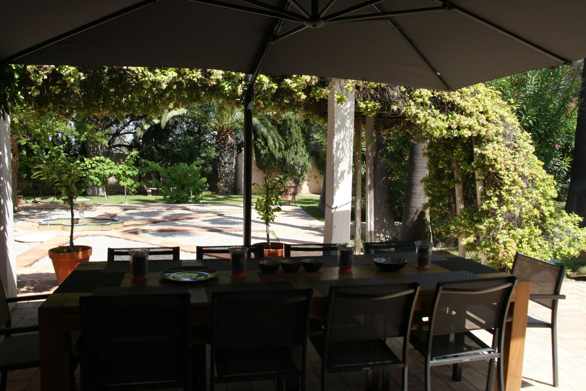 Vine-shaded pergola with a long dining table at Your Algarve Oasis