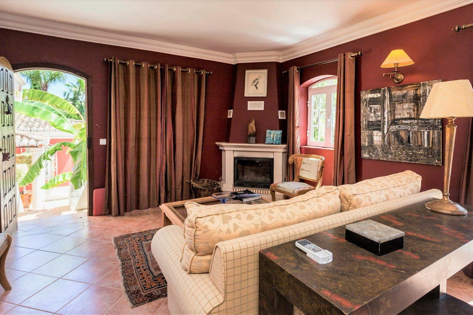 Sitting room in deep red with a fireplace at Your Algarve Oasis