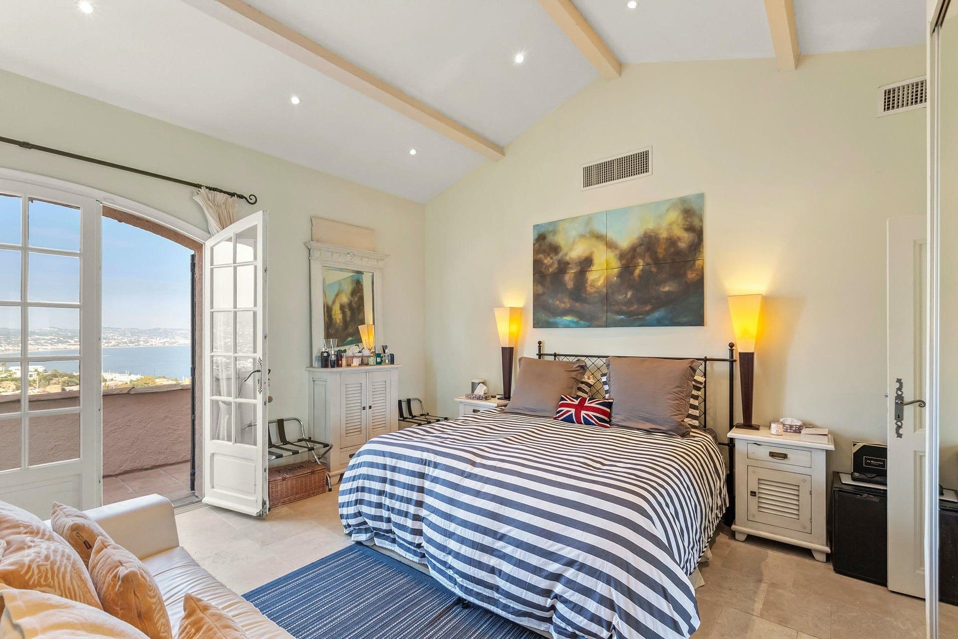 Bedroom with striped nautical bedding and a distant sea view through the window
