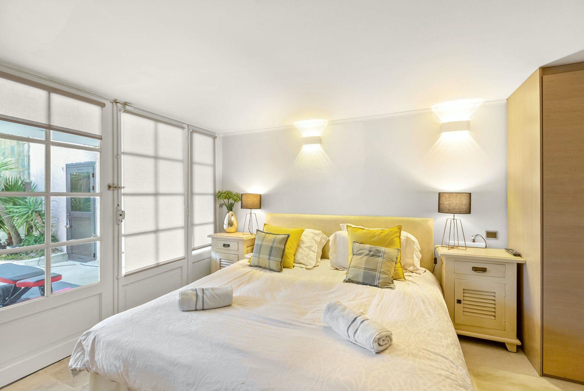 Bedroom with yellow accent cushions, twin nightstands and garden-view windows