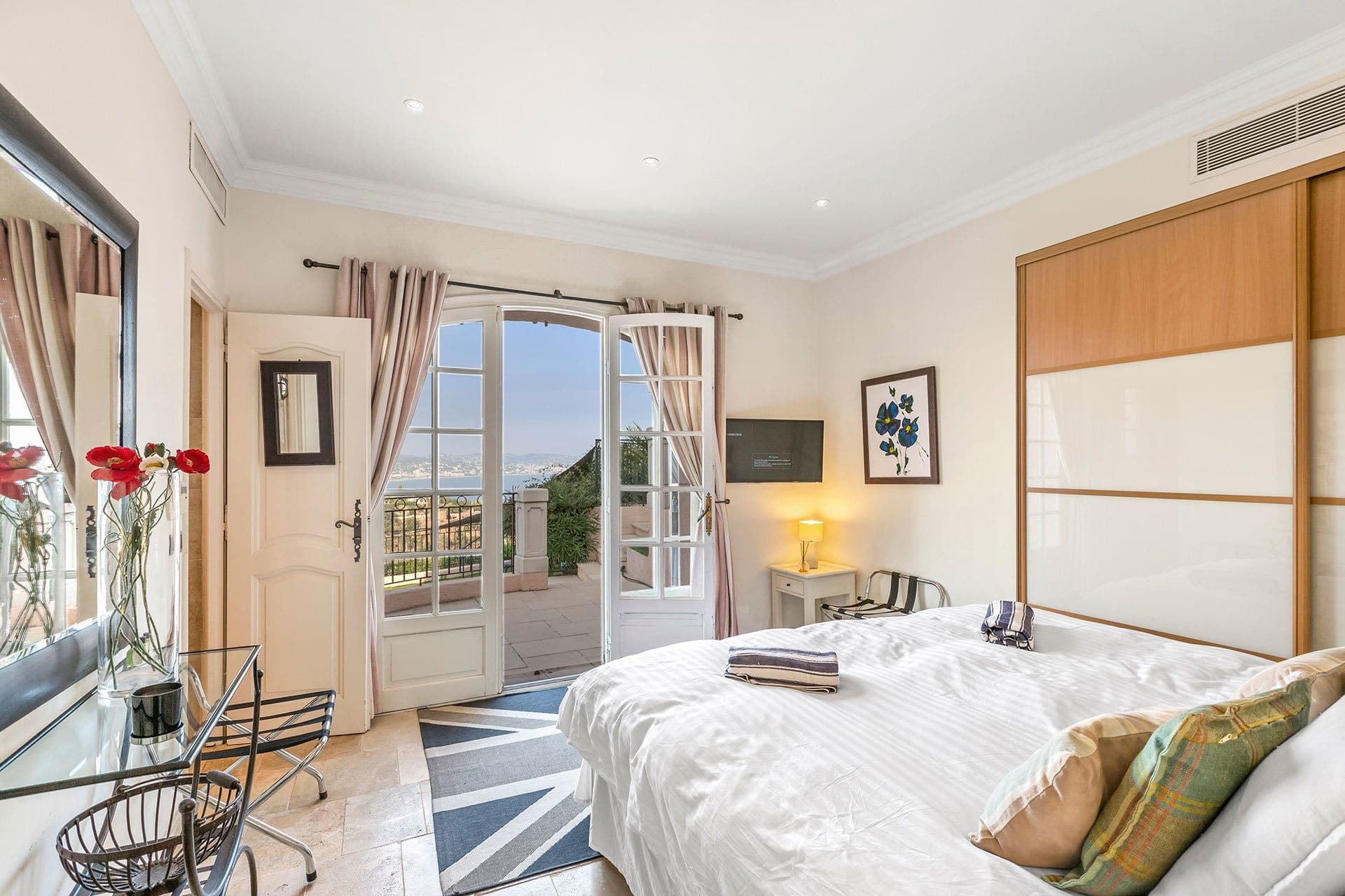 Guest bedroom with floral bedding and French doors opening to a private terrace