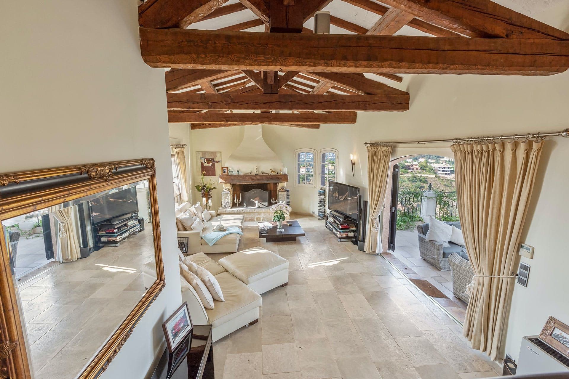 Second living area with large gilt mirror, sofas and beamed ceiling