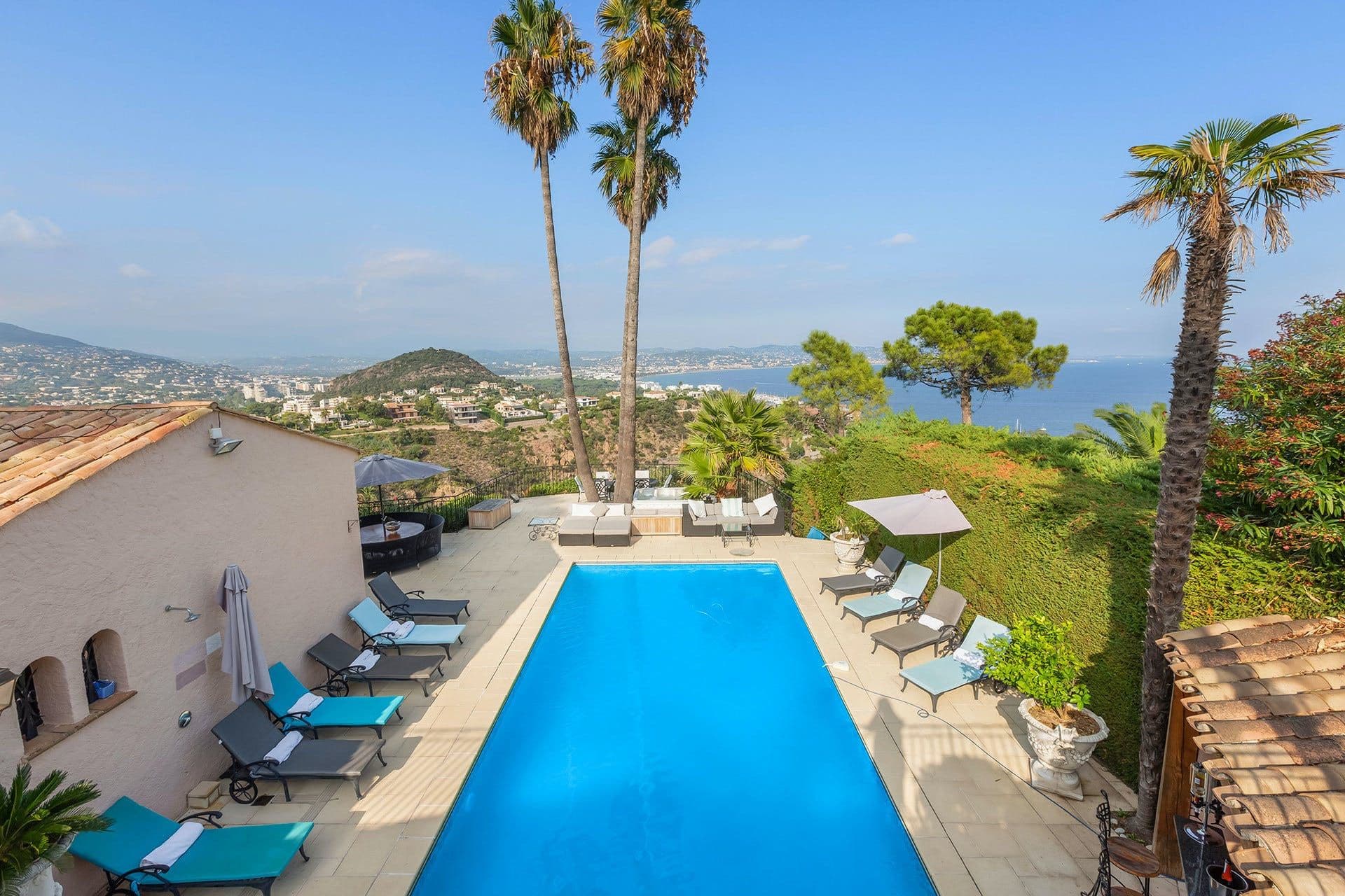 Long infinity-edge pool at Villa Cactus in Théoule-sur-Mer, framed by palm trees with panoramic French Riviera sea views
