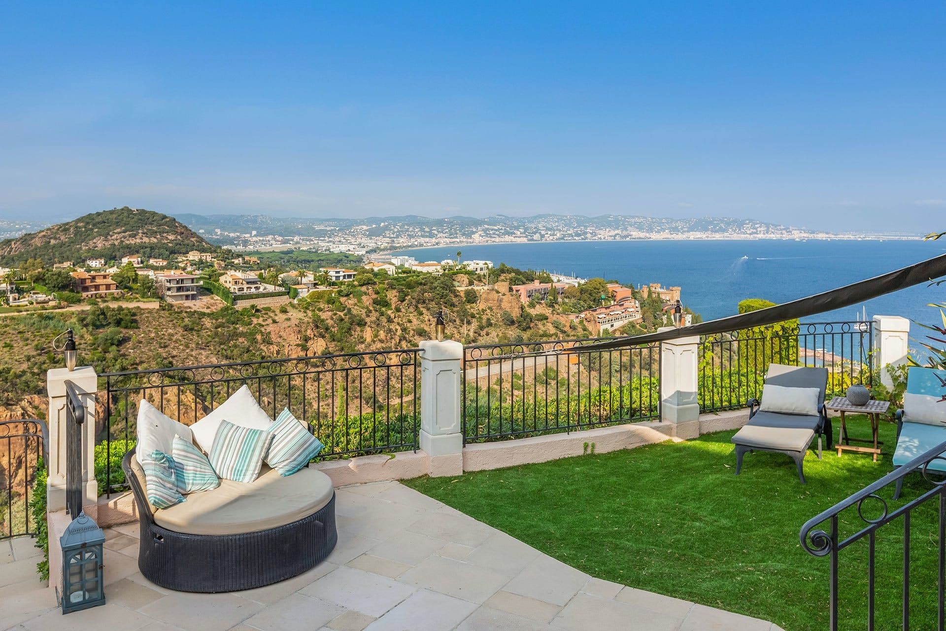 Furnished terrace with day bed and lawn overlooking the Mediterranean coastline at Villa Cactus