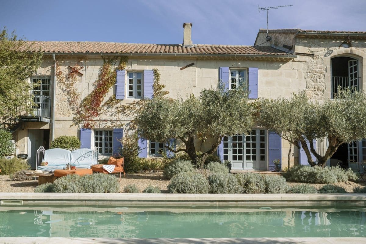 The French Effect's stone Provencal farmhouse facade with pool and olive trees