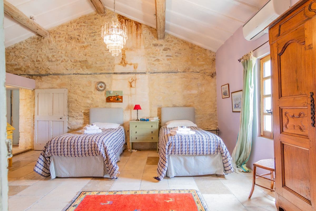 Twin bedroom with iron bedsteads and red rug