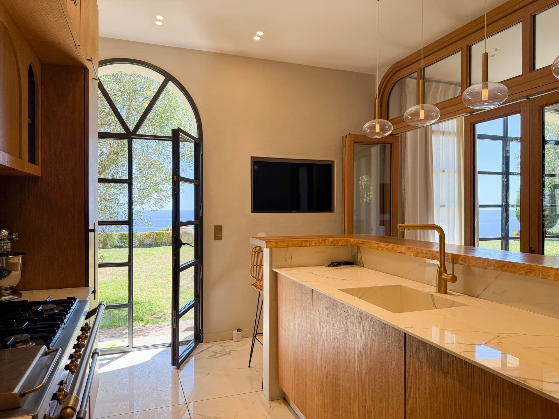 Kitchen with a marble island, oak units and a range beside arched garden doors at An Azure Vision, Cannes