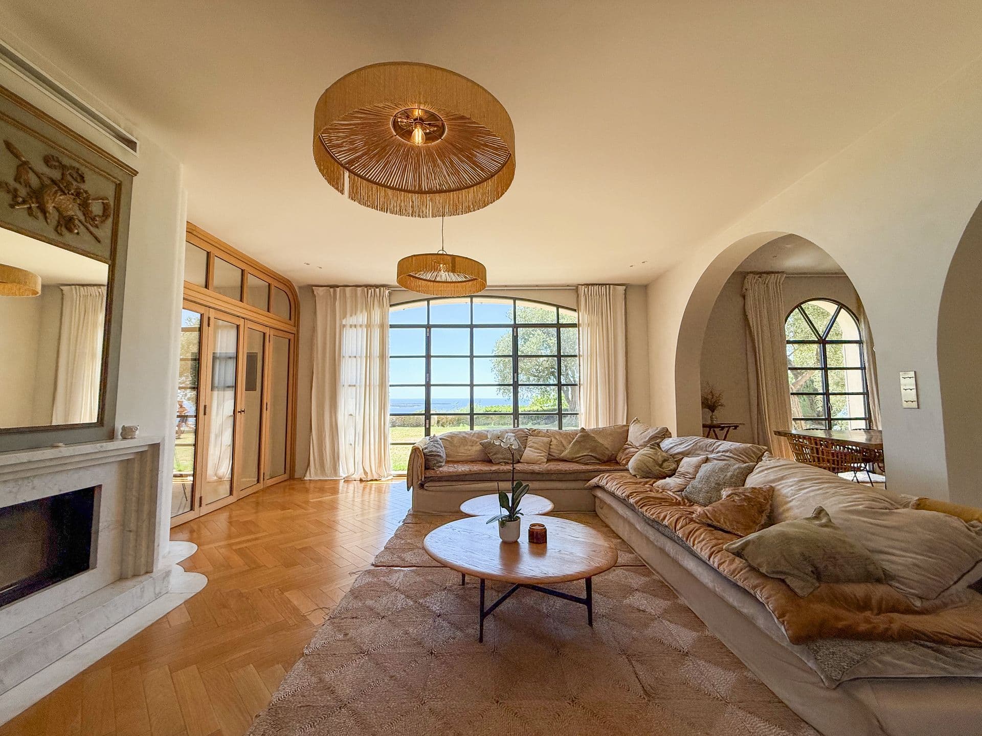 Living room with a stone fireplace, deep sofas and a sea-view window at An Azure Vision, Cannes