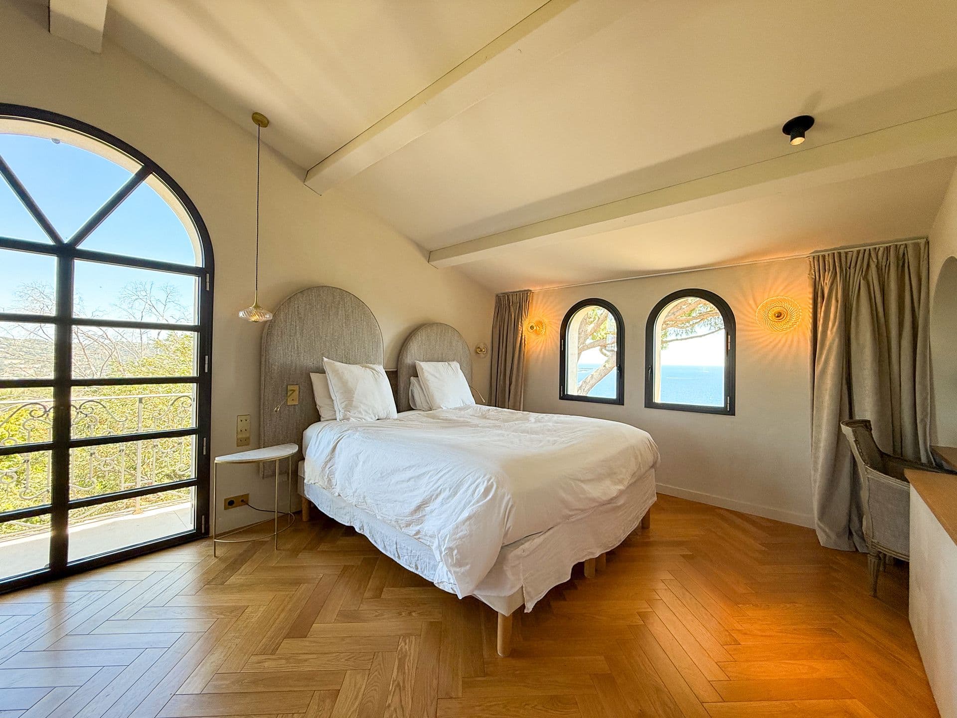 Master bedroom with arched windows framing the sea at An Azure Vision, Cannes