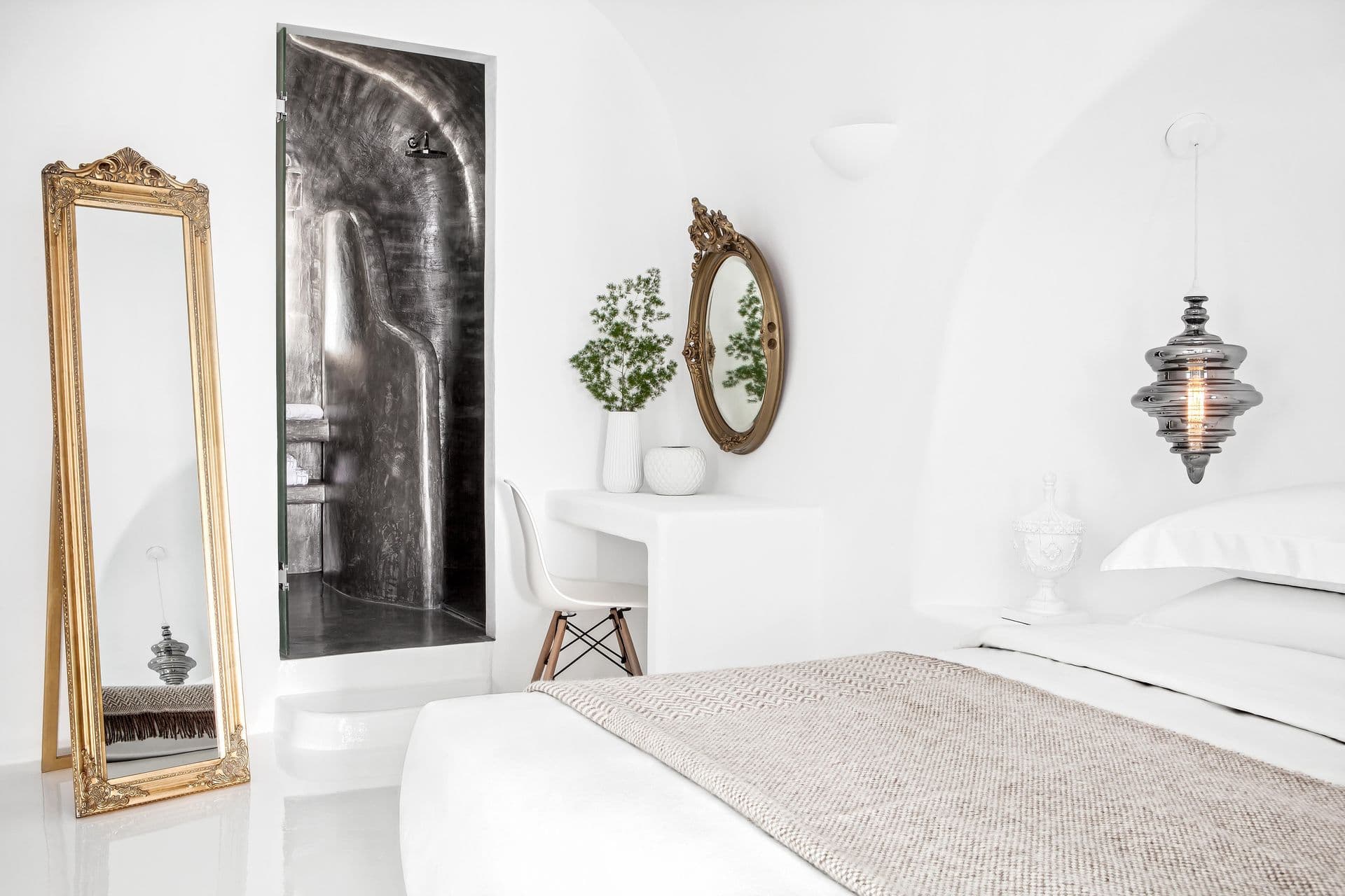 White cave bedroom with a full-length gilt mirror and microcement shower niche at Cave Chic, Imerovigli, Santorini