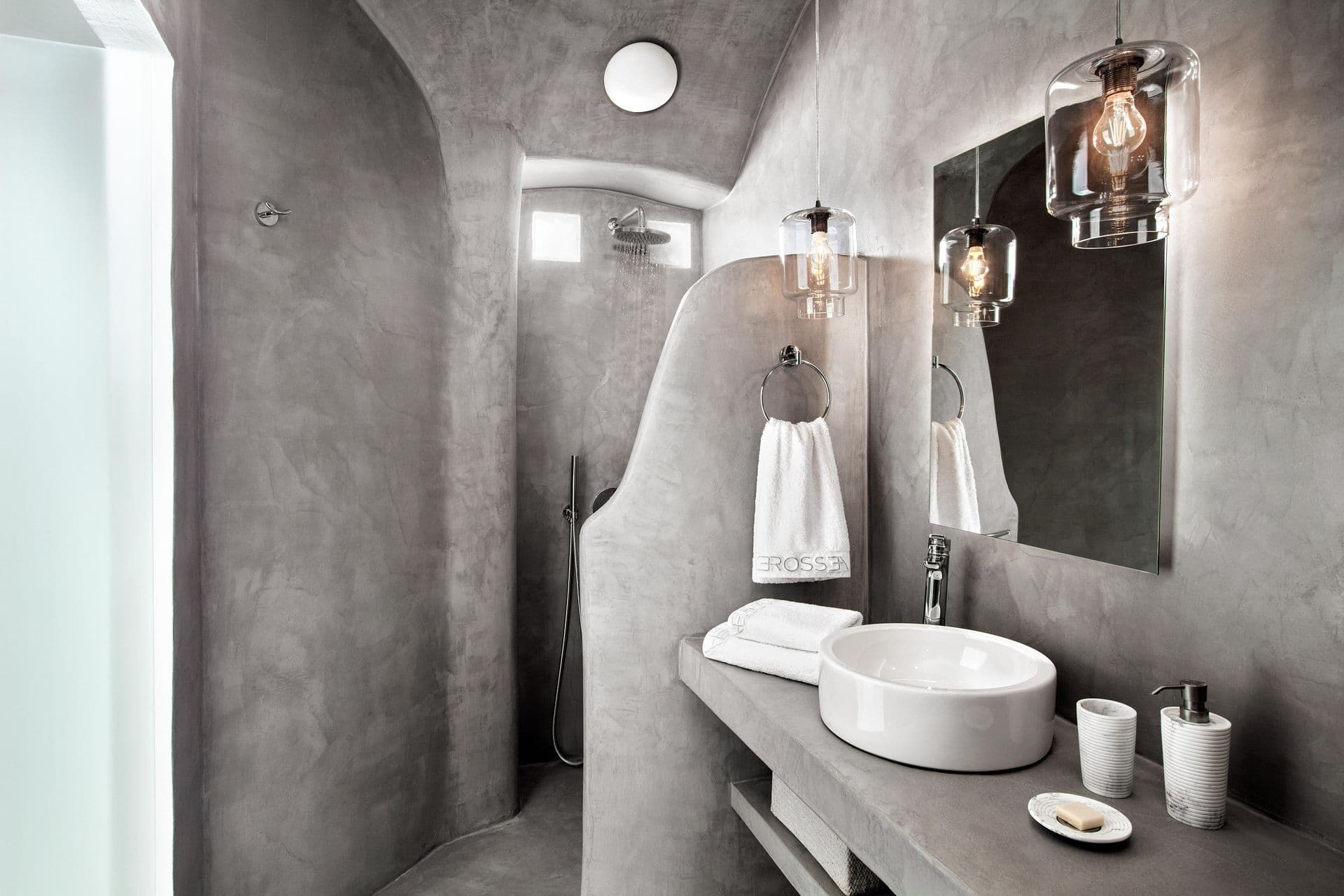 Grey microcement en-suite with twin vessel basins and a walk-in shower at Cave Chic, Imerovigli, Santorini