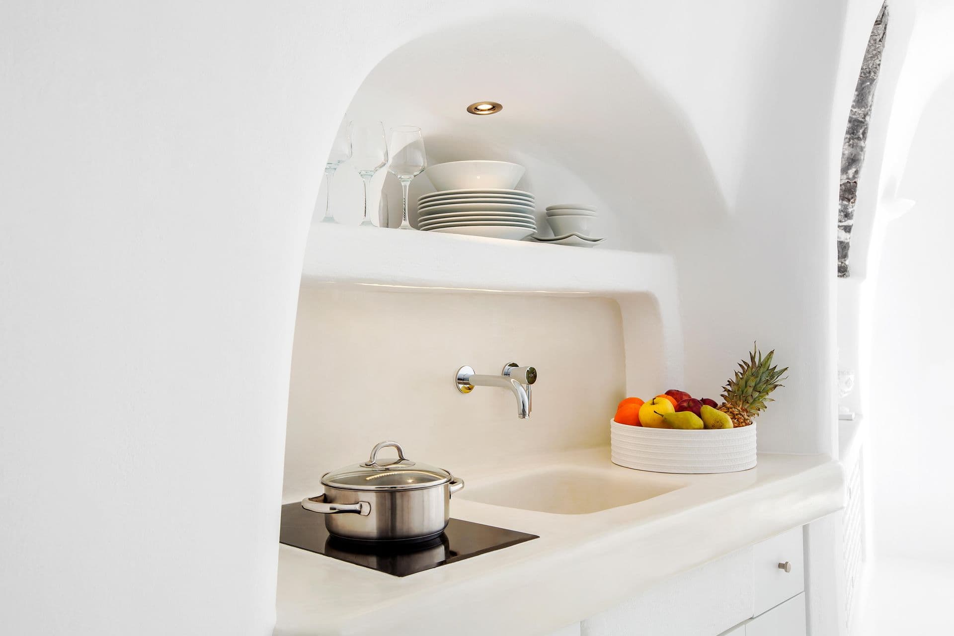 Sculptural white cave kitchen with a hob and sink set into the wall at Cave Chic, Imerovigli, Santorini