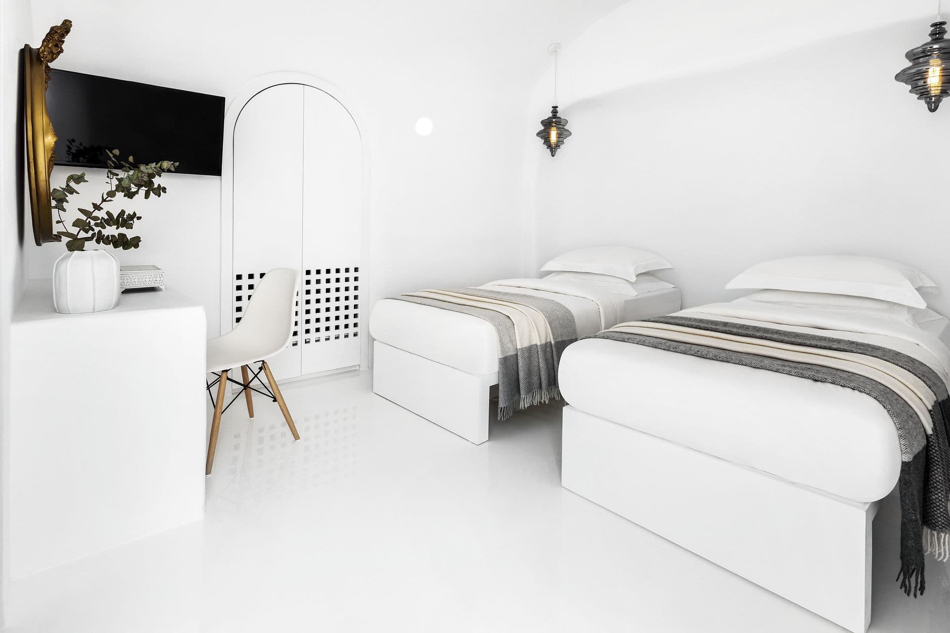White cave twin bedroom with a television and desk chair at Cave Chic, Imerovigli, Santorini