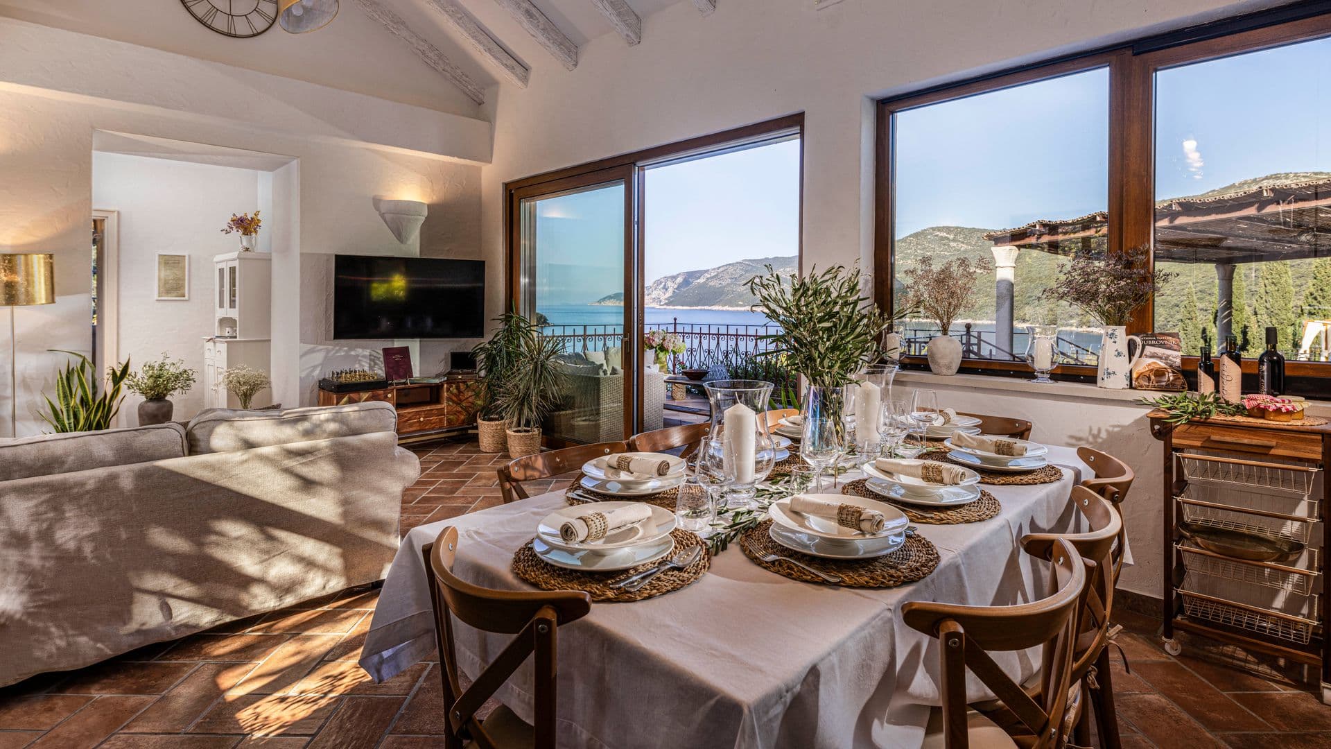 Dining table set beside large windows onto the sea and hills at Aria to the Adriatic, Croatia