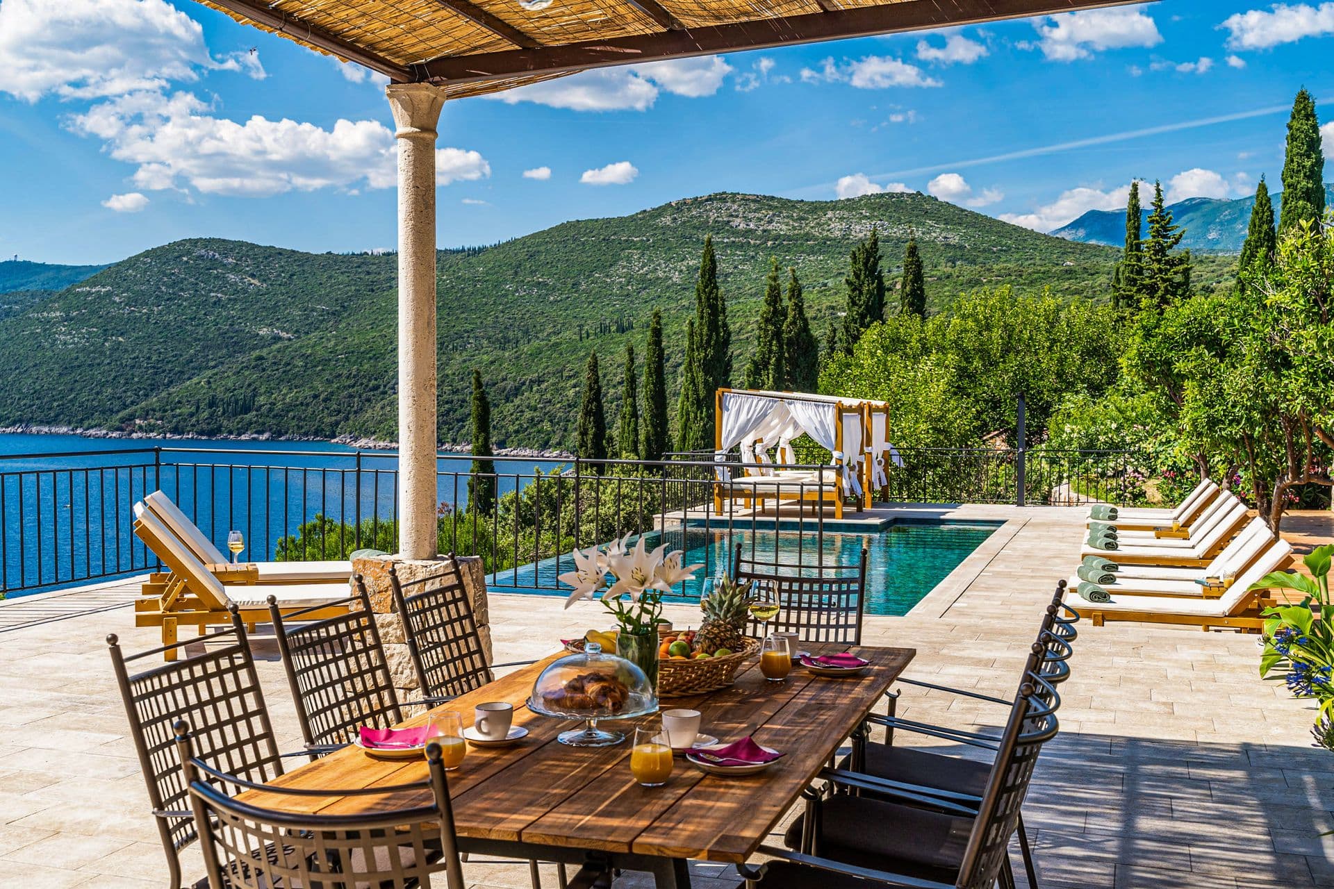 Outdoor dining table set beside the pool with a bay view at Aria to the Adriatic, Molunat, Croatia