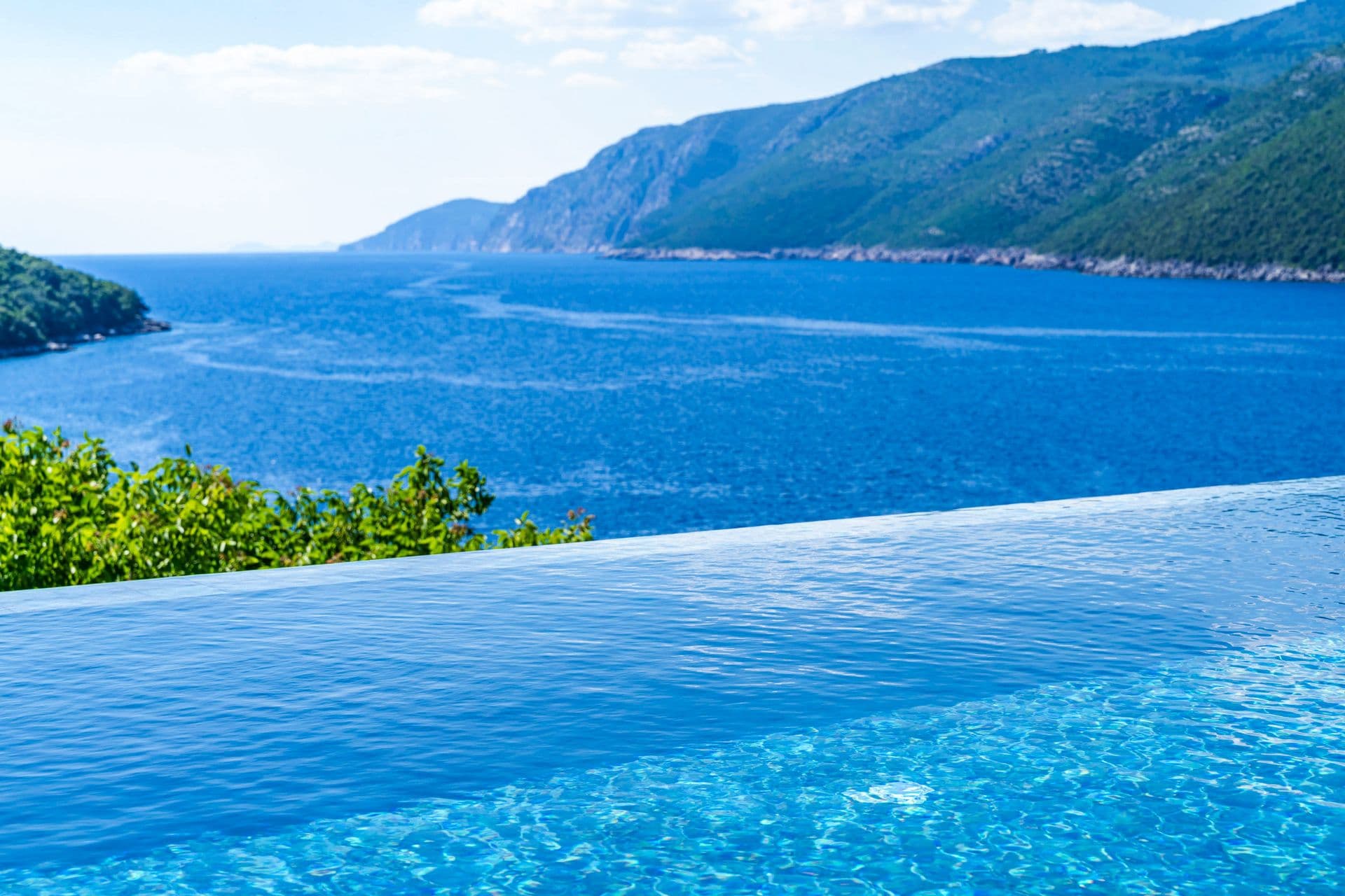 Infinity-edge pool meeting the blue of the Adriatic and a distant headland at Aria to the Adriatic, Croatia