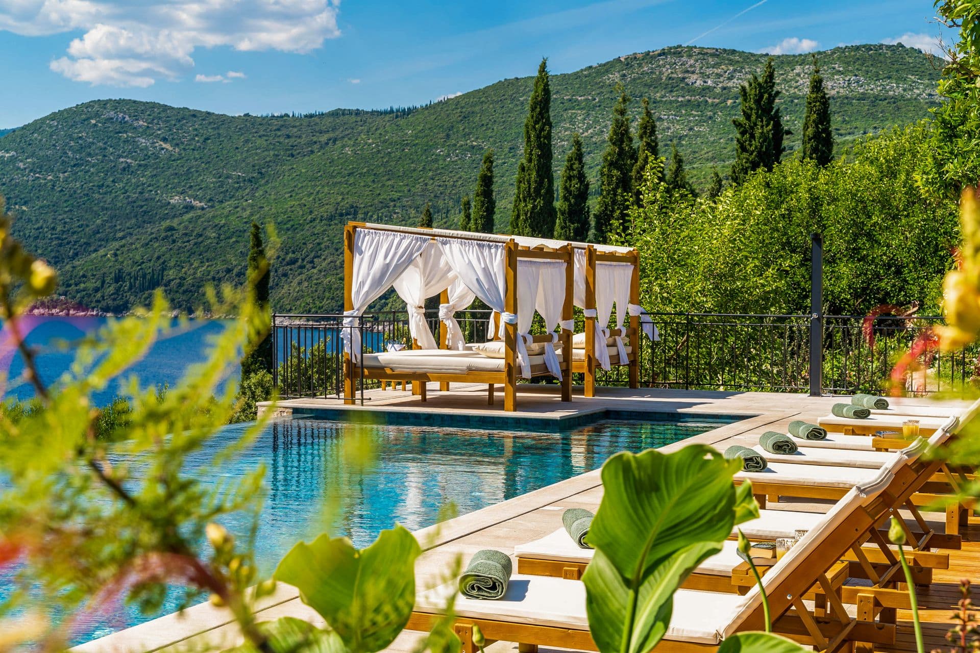 Poolside canopied day beds framed by cypresses at Aria to the Adriatic, Molunat, Croatia