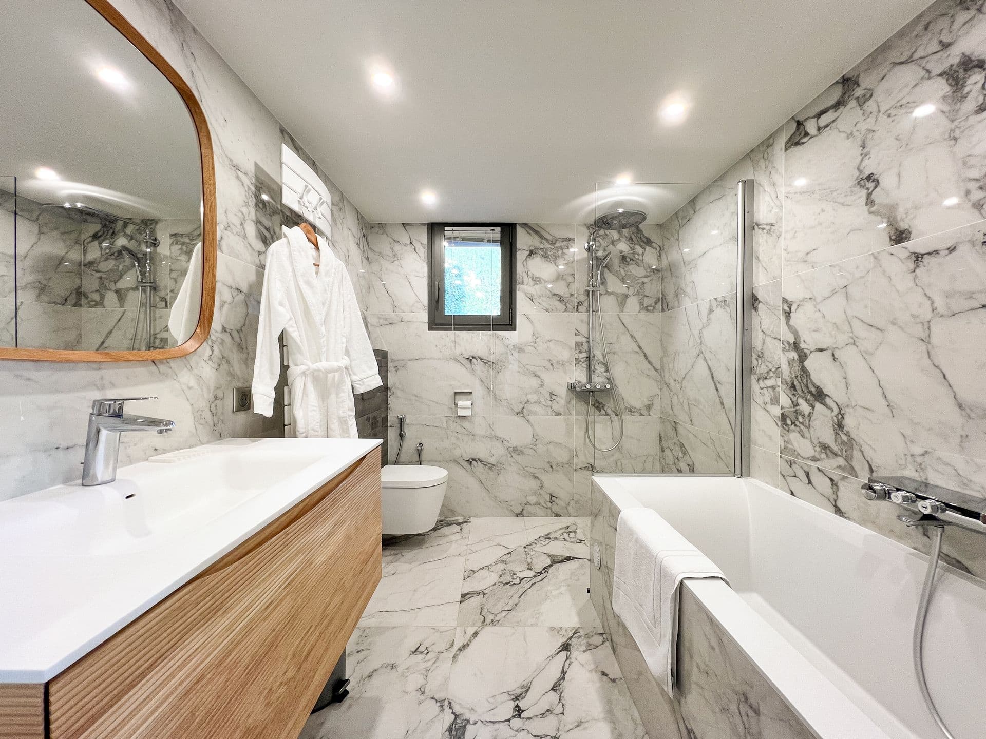 Marble bathroom with a built-in bathtub, twin sink and mirrored wall