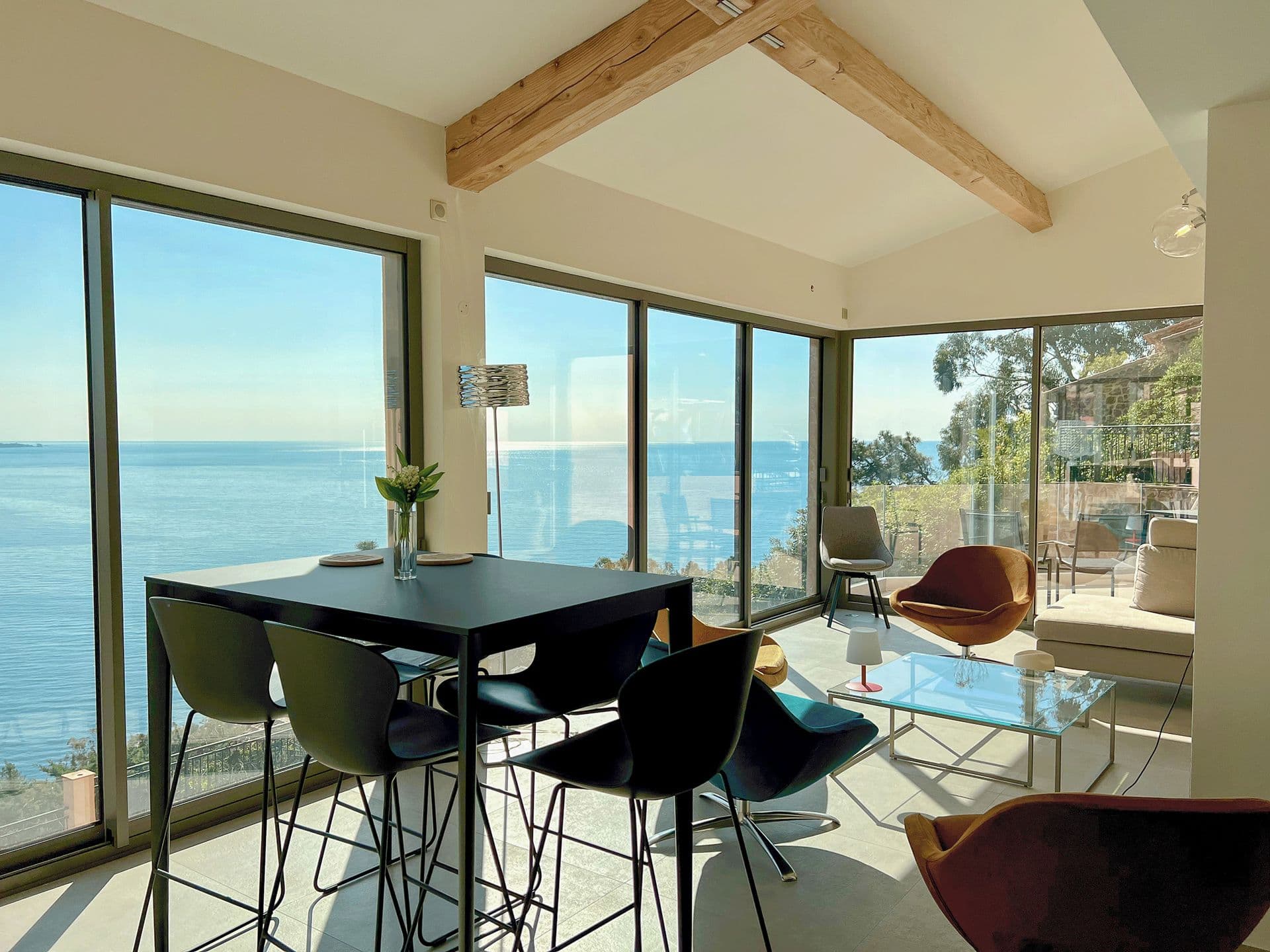 Indoor dining table for six beside floor-to-ceiling windows overlooking the sea