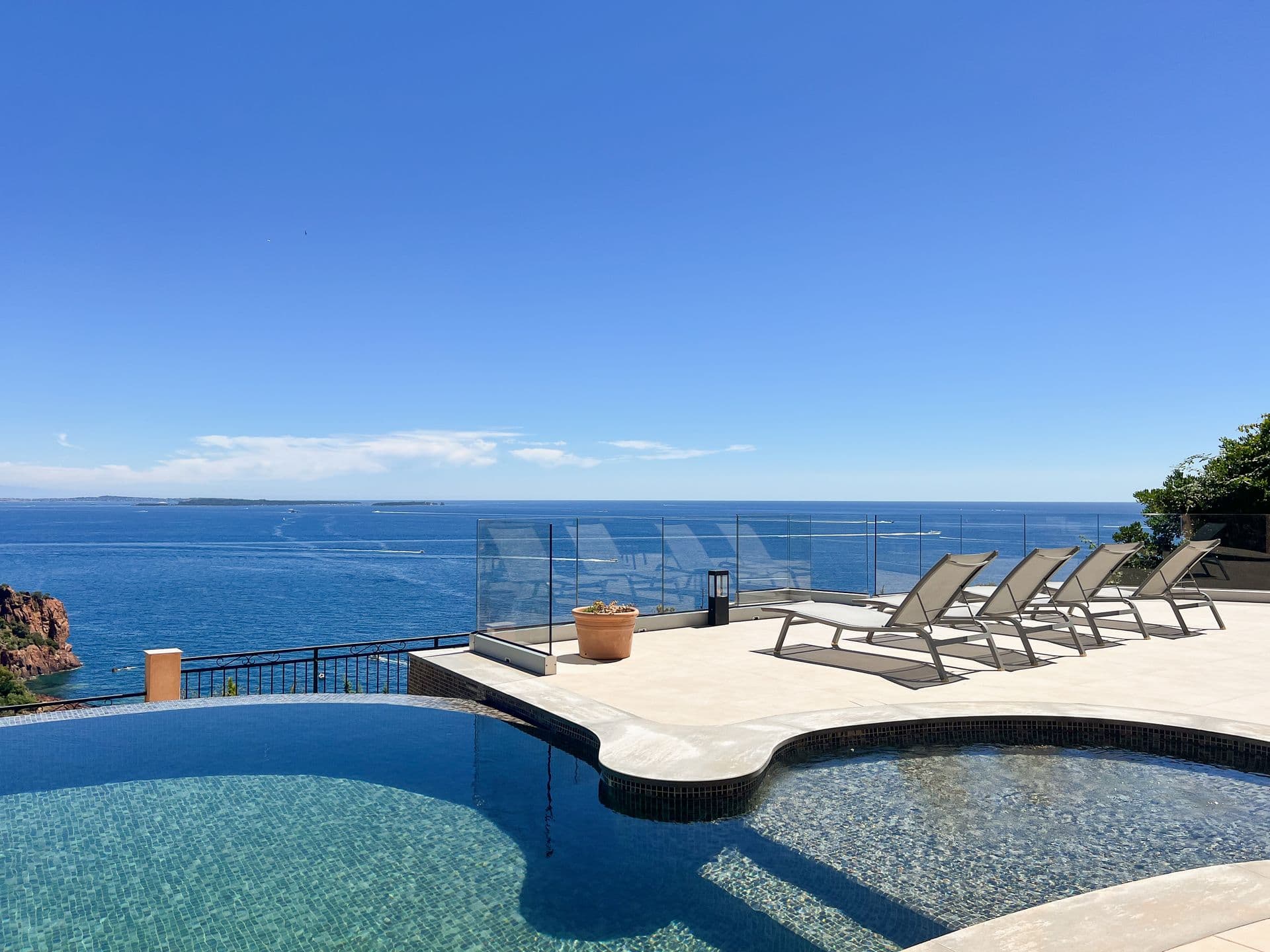Curved infinity pool and sun terrace framed by rocky coastal pines
