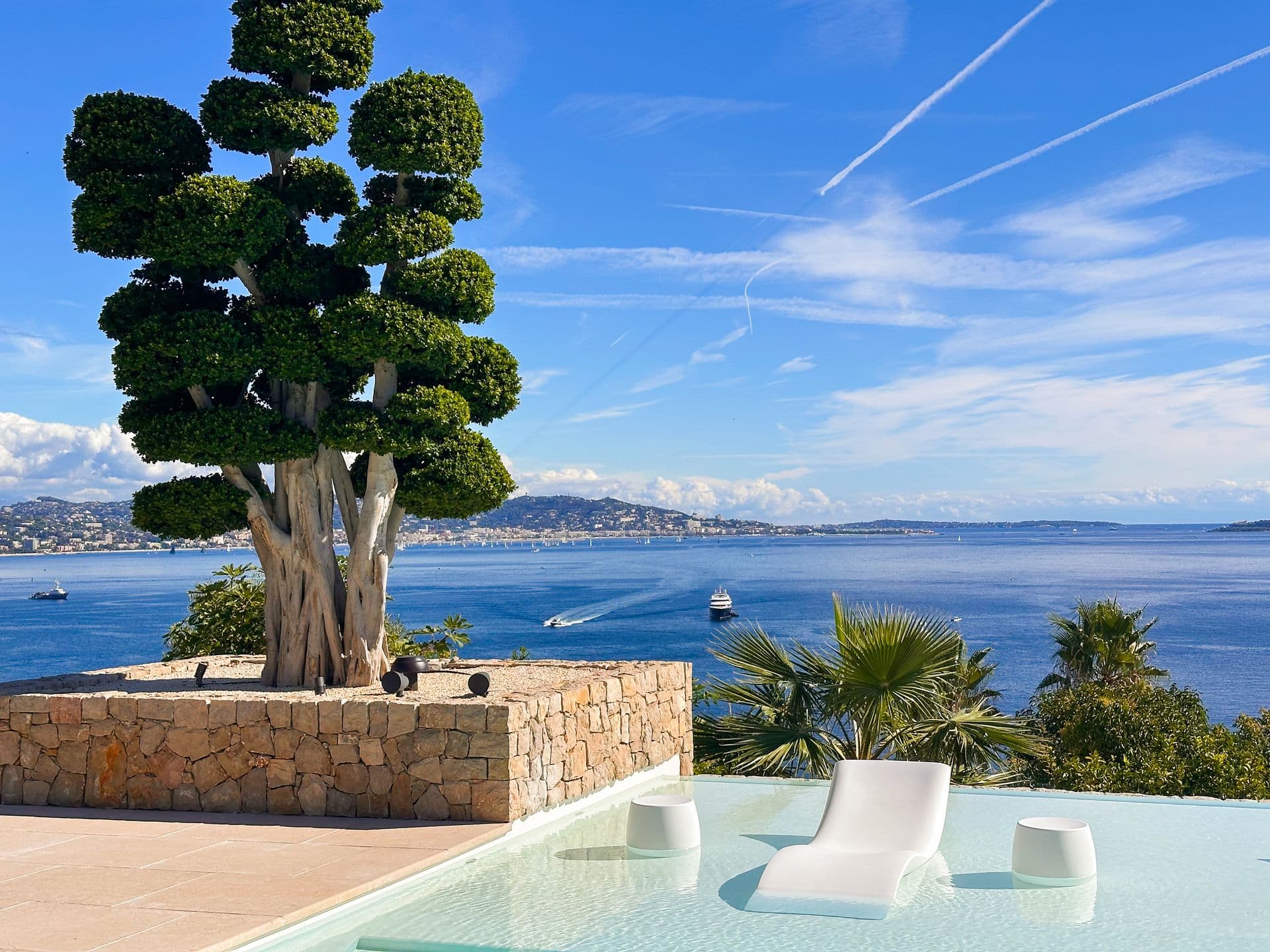 Stone terrace with sculpted topiary framing an open sea view