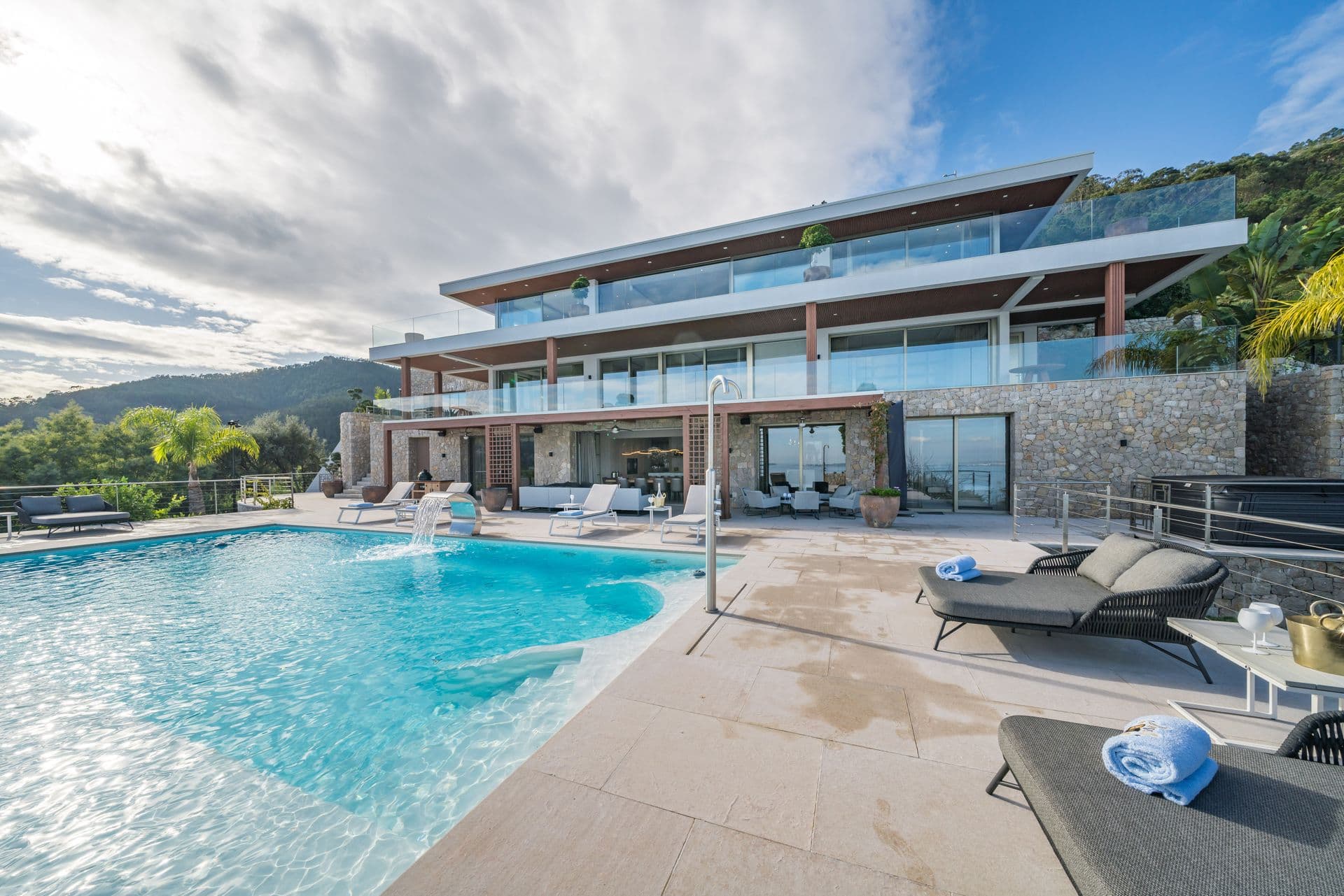 Side view of the villa and pool terrace with the coastal hills behind