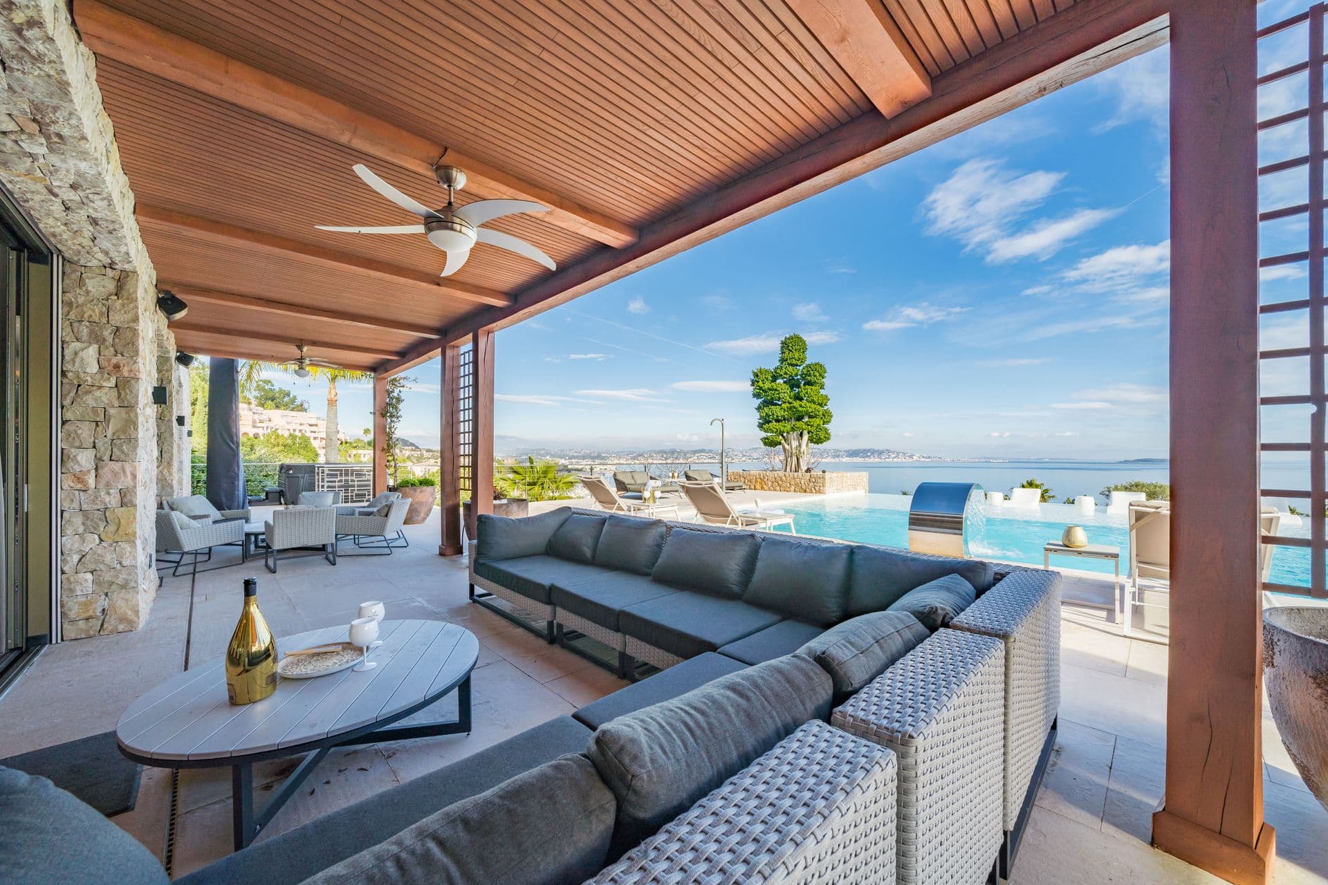Shaded terrace seating area beside the pool with coastal views