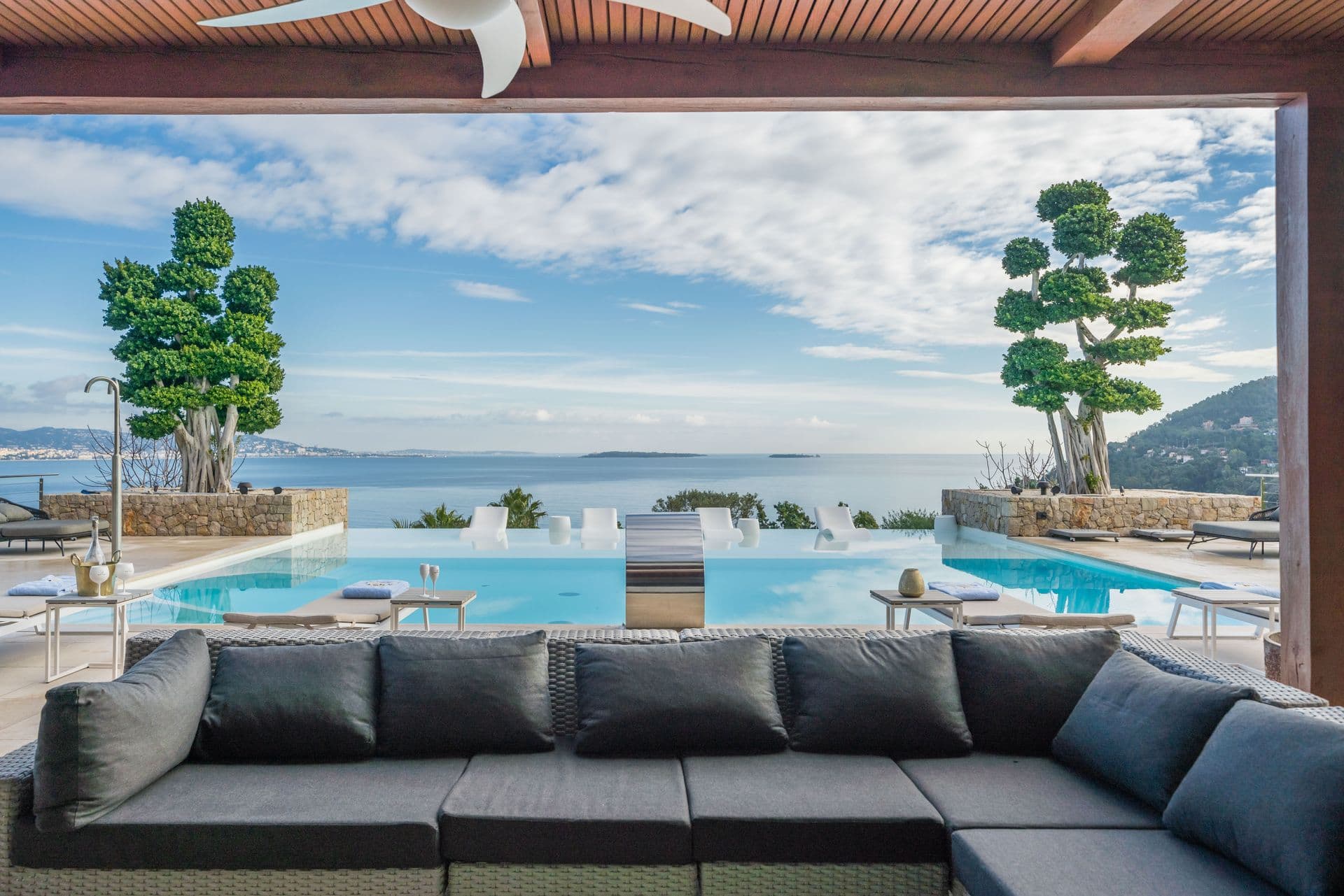Covered outdoor lounge with deep sofas overlooking the pool and sea