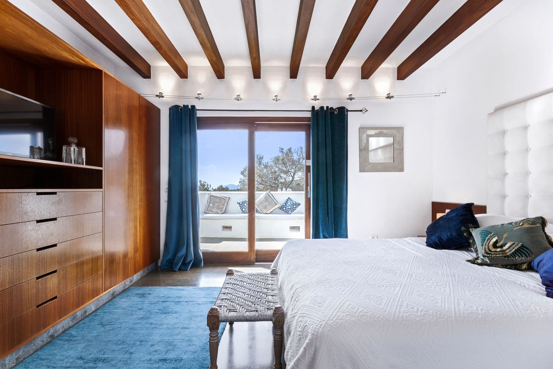 Bedroom with wooden dresser and blue curtains at Ode to Balearic Sunsets, Ibiza