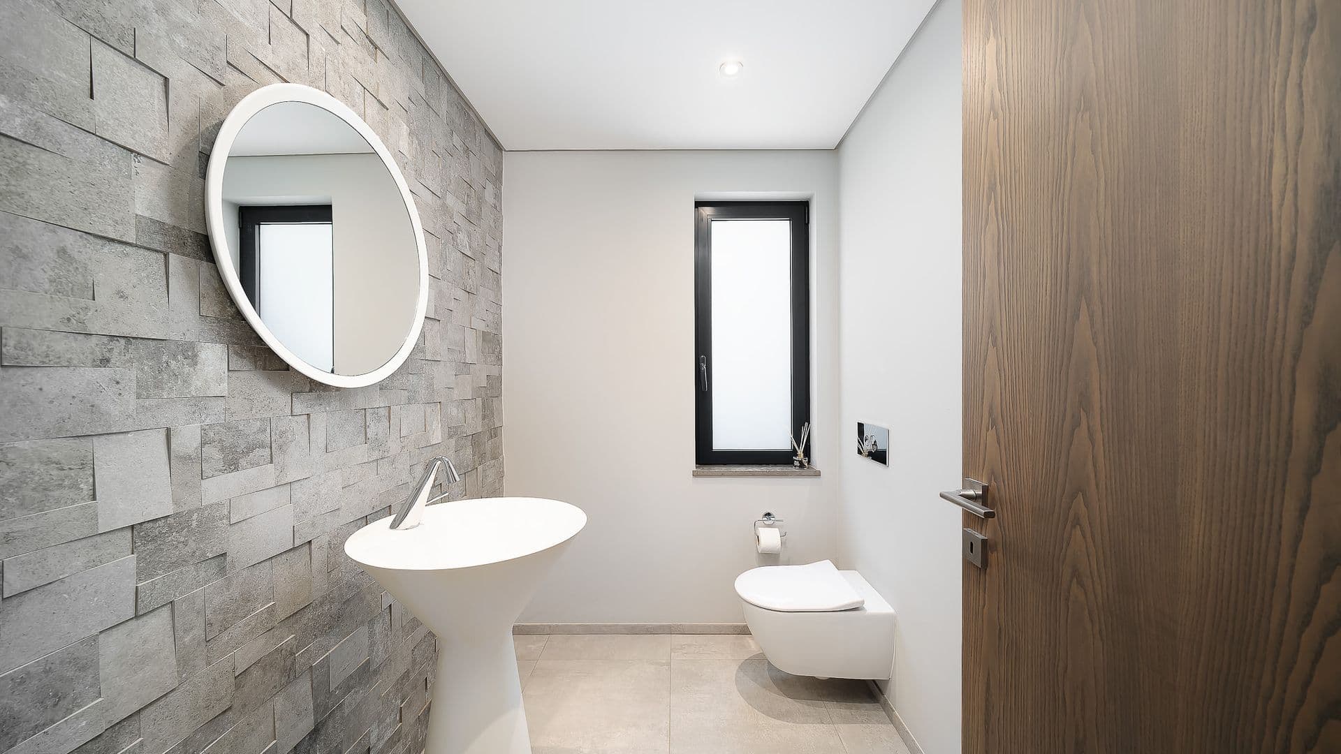Bathroom with a stone feature wall and round backlit mirror