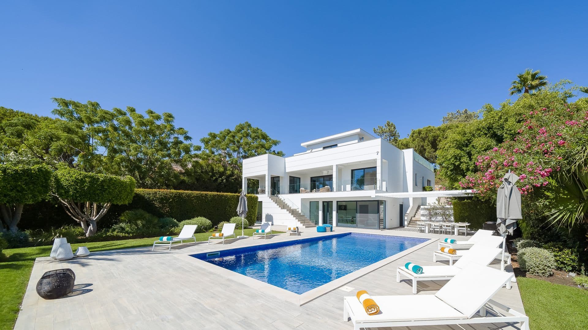 Modern white villa with a long rectangular pool set within a manicured garden