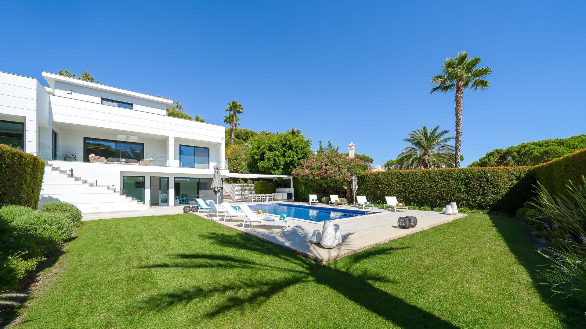 Wide view of the villa across an expansive manicured lawn and pool terrace