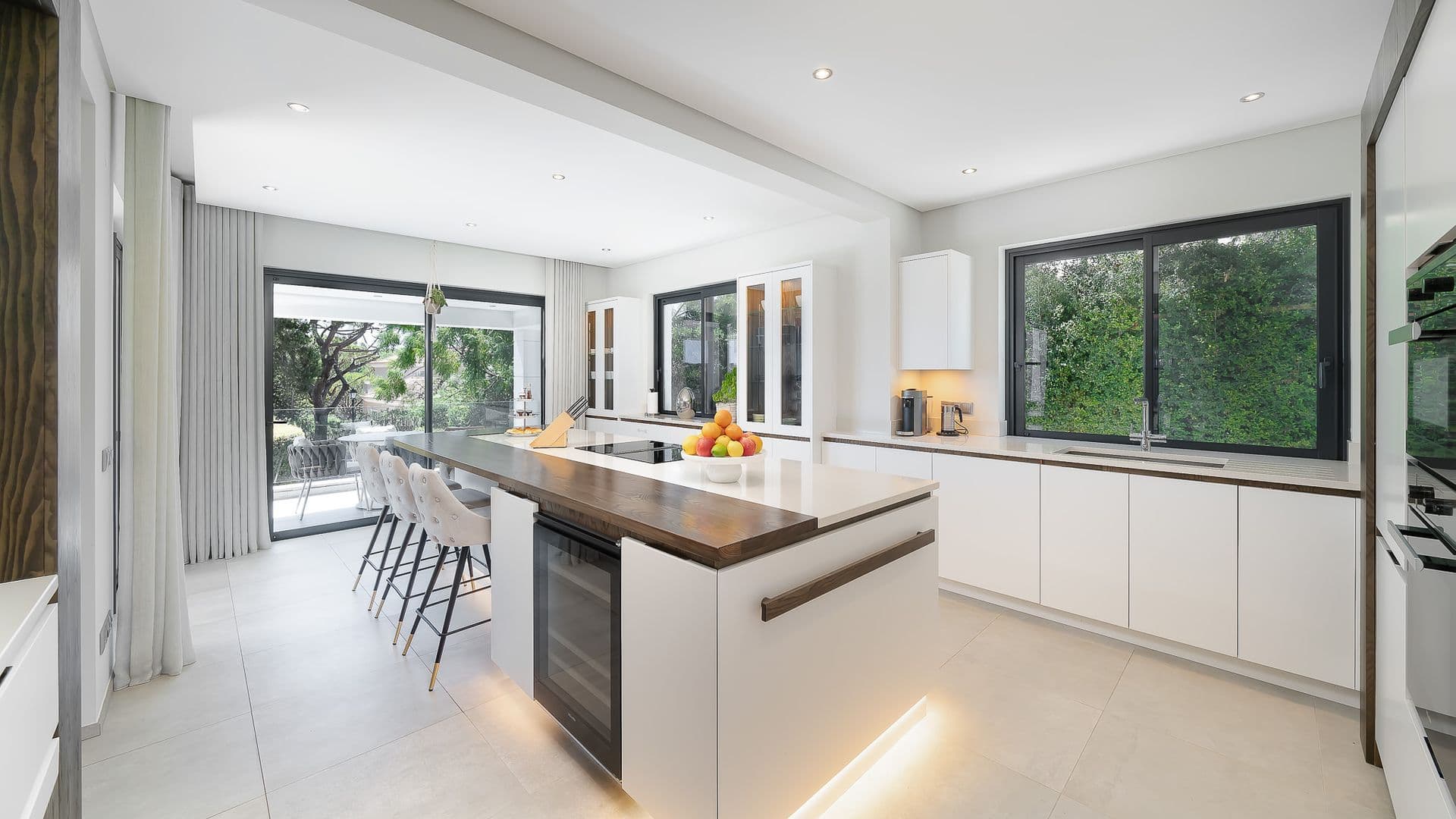 White kitchen island with wood countertop and bar stool seating