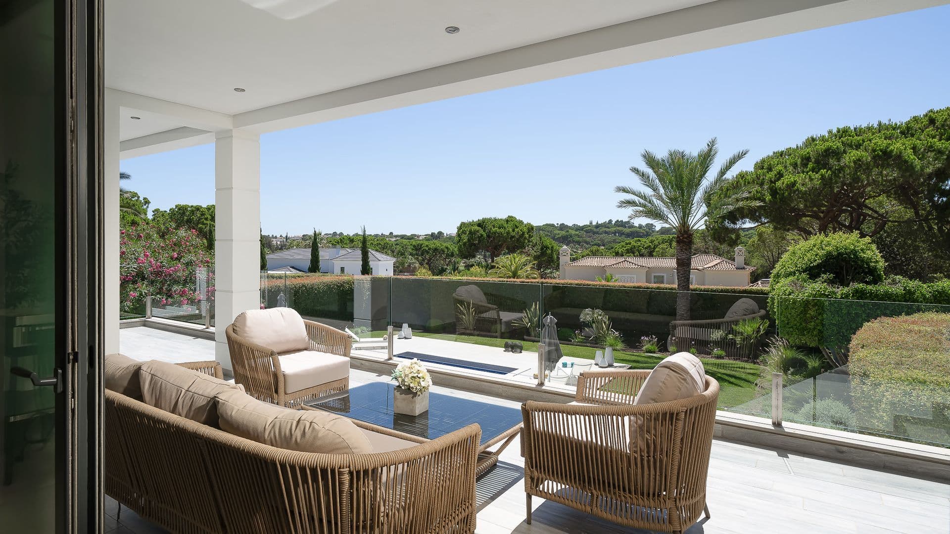 Covered terrace lounge with woven armchairs looking out over the garden