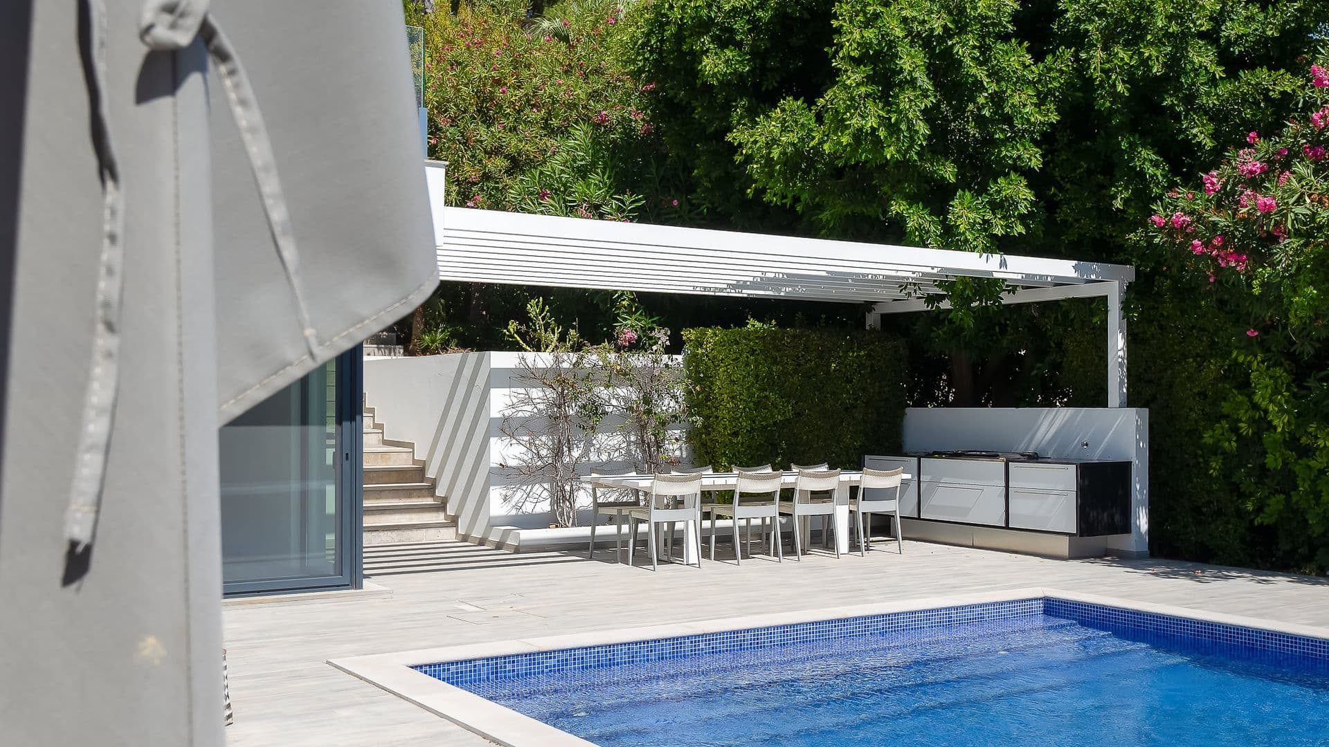 Poolside terrace with a shaded outdoor dining table and pergola