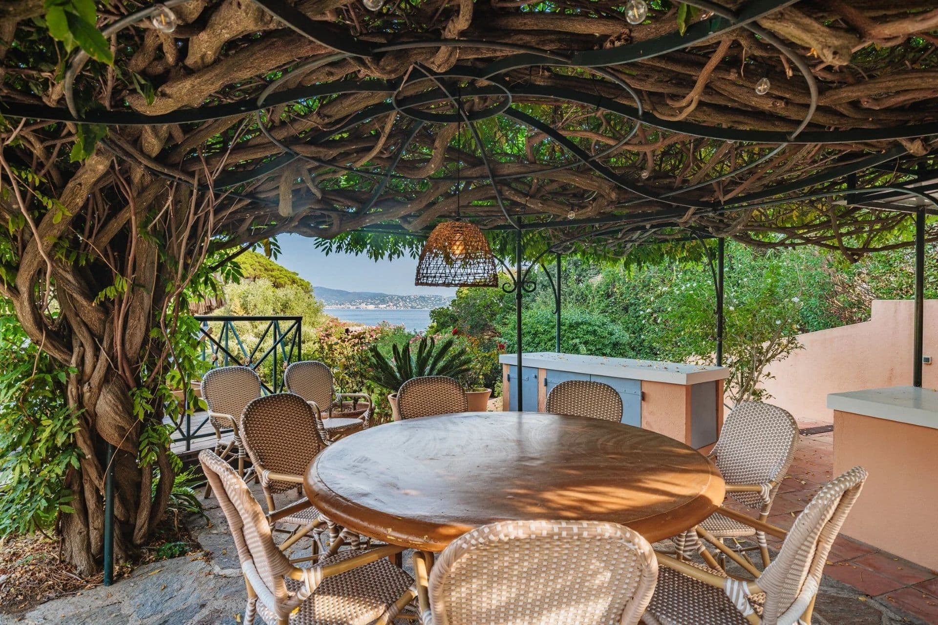 Outdoor dining table beneath a vine-covered pergola at South Sea Bliss