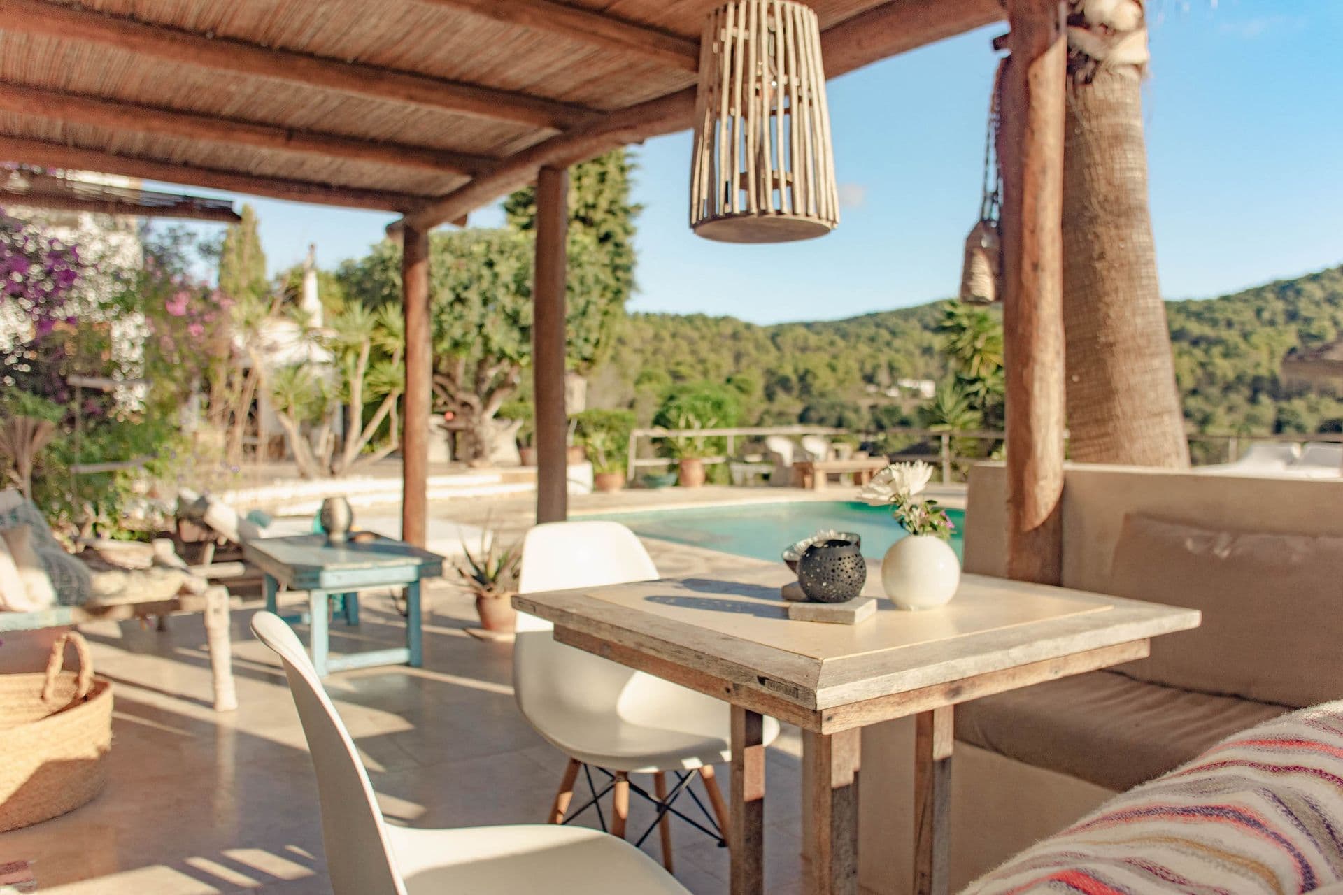 Covered terrace with sofa seating and dining table overlooking the pool