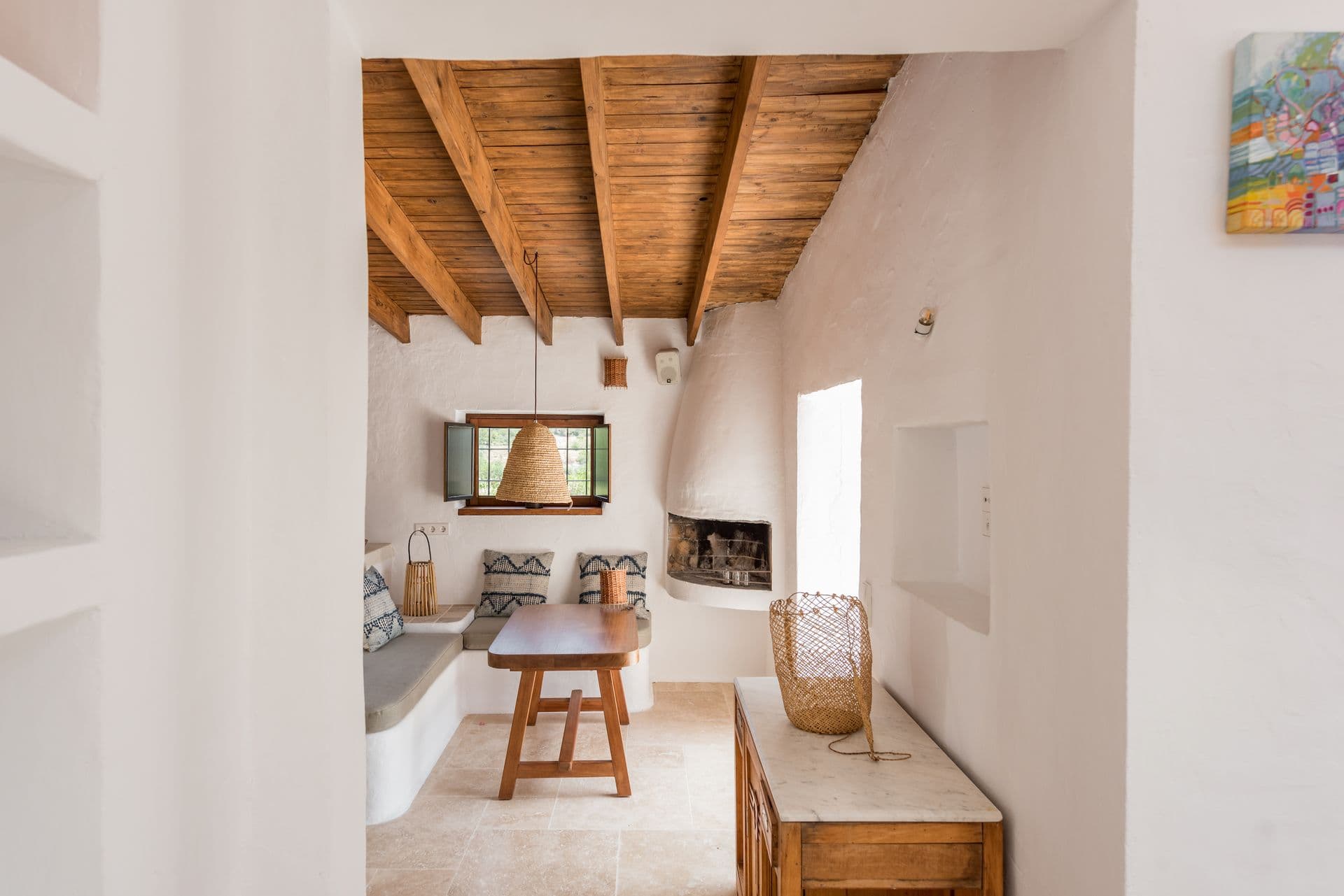 Whitewashed hallway with exposed wood beams and a corner fireplace