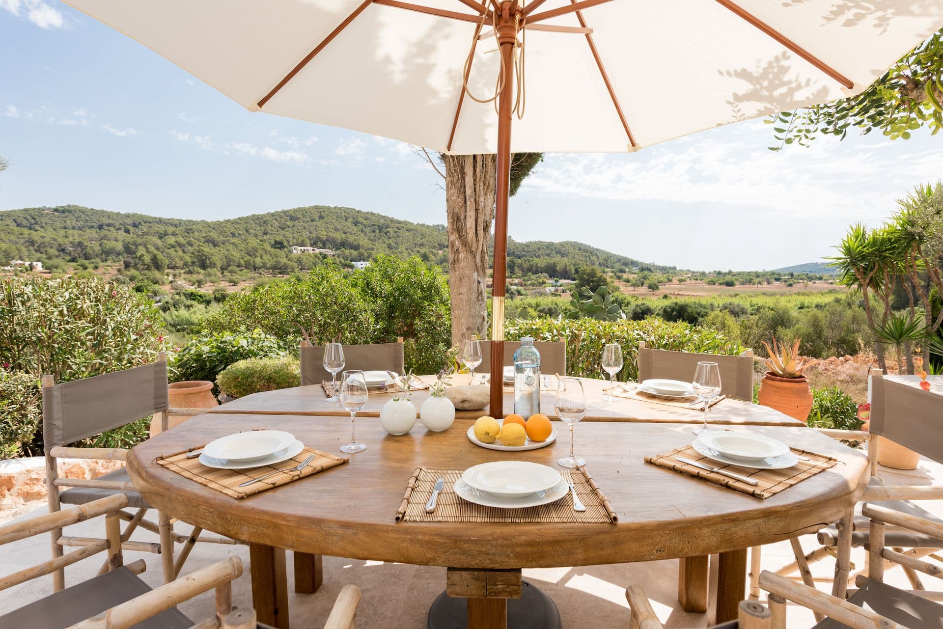 Round outdoor dining table set for a meal with rolling hills in the background