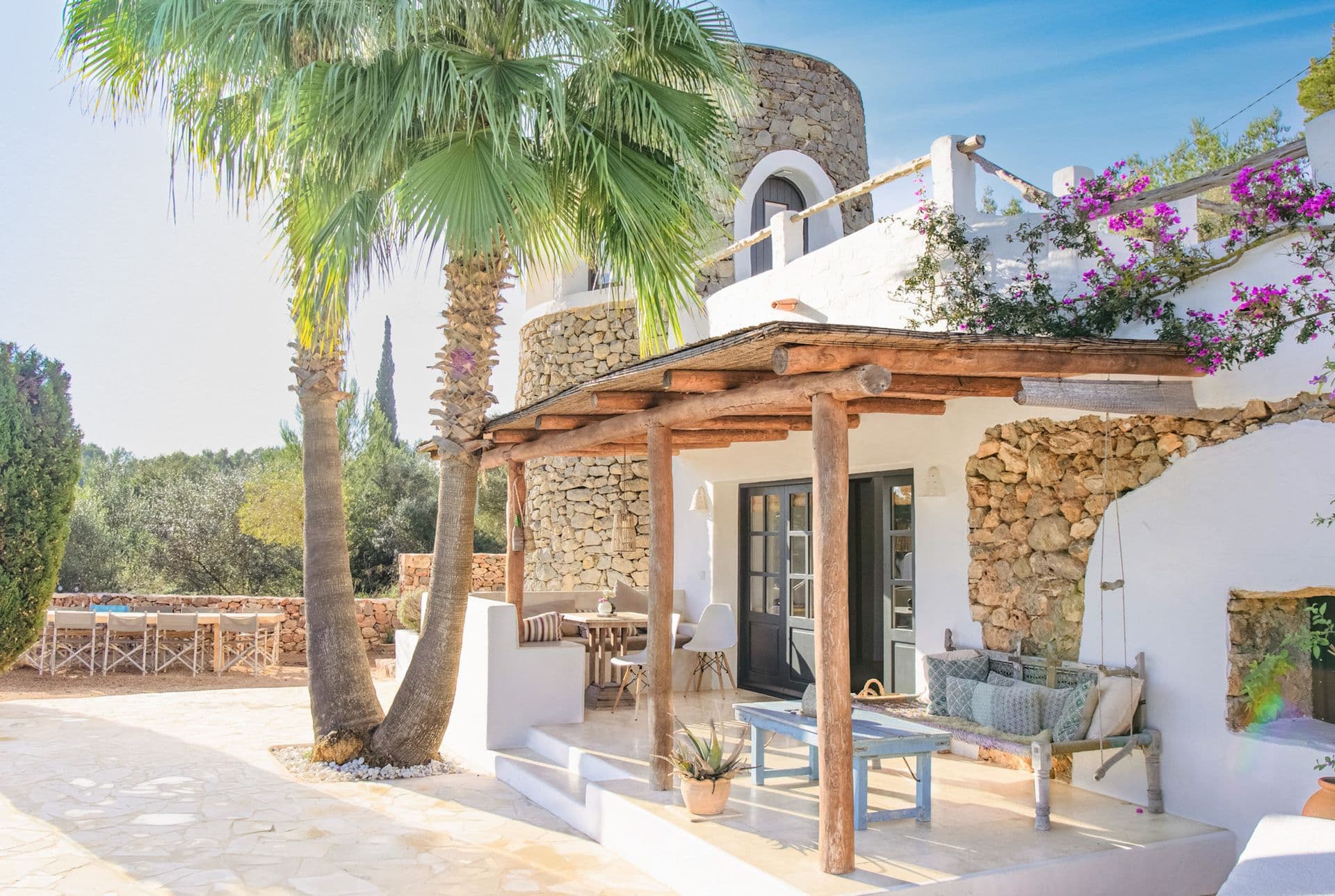 Wooden pergola terrace beside a stone tower and palm tree