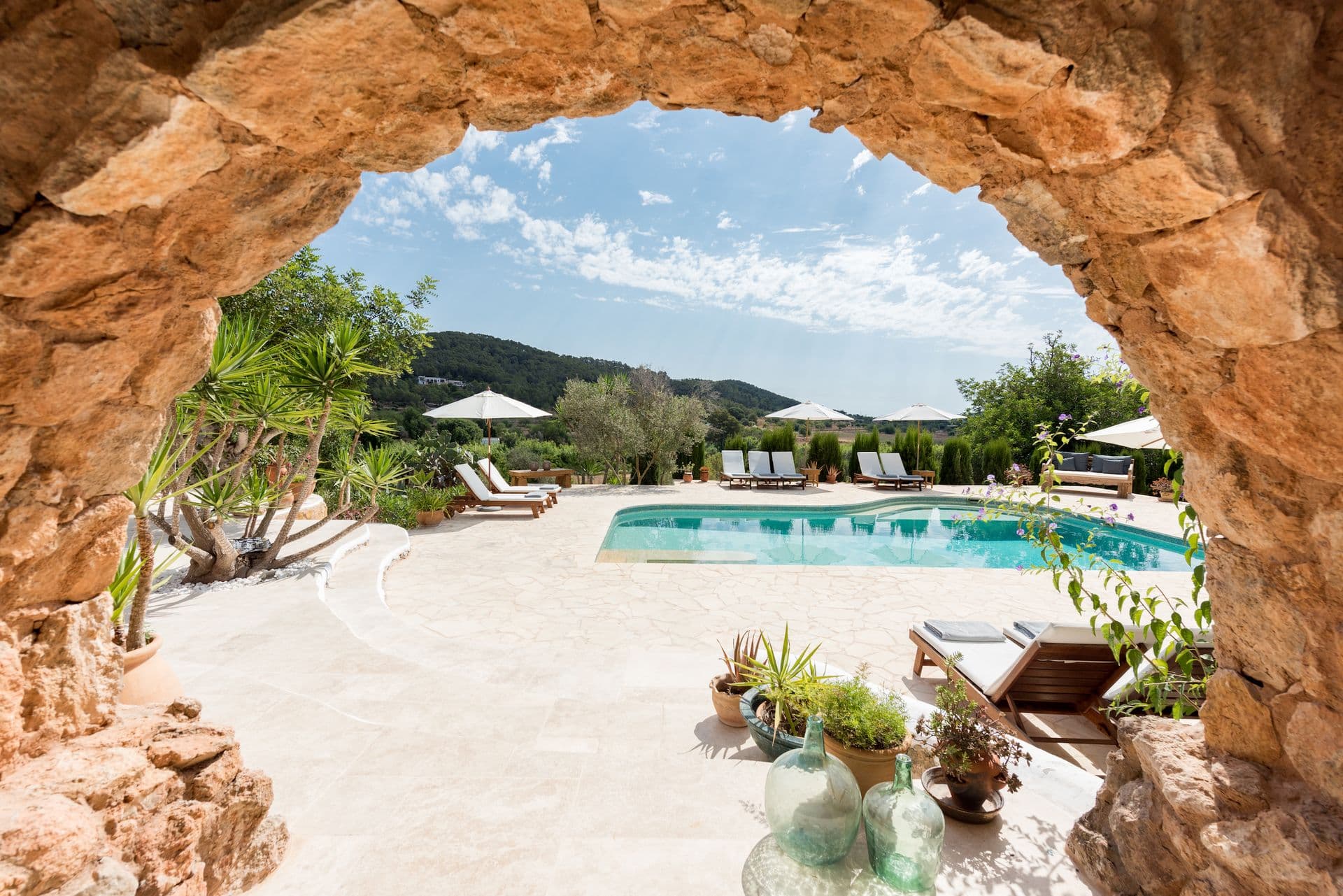 Rustic stone archway framing a view of the pool and hills beyond
