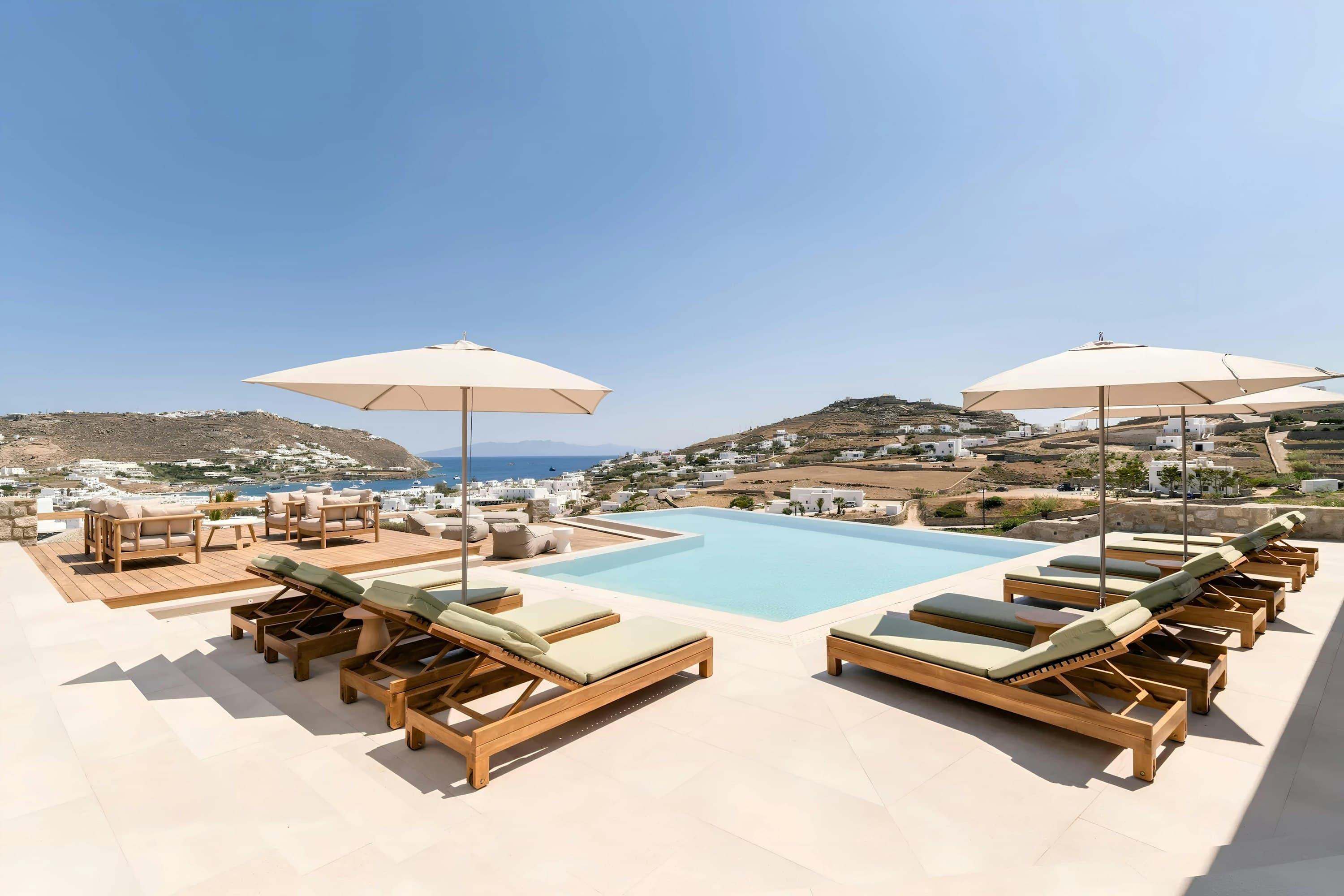 My Aegean Gem infinity pool with teak loungers overlooking Mykonos coast, Ornos, Cyclades Islands, Greece