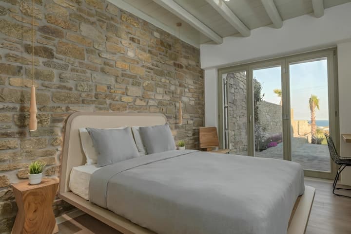 Seashore Silhouette master bedroom with stone wall and terrace access, Mykonos, Greece