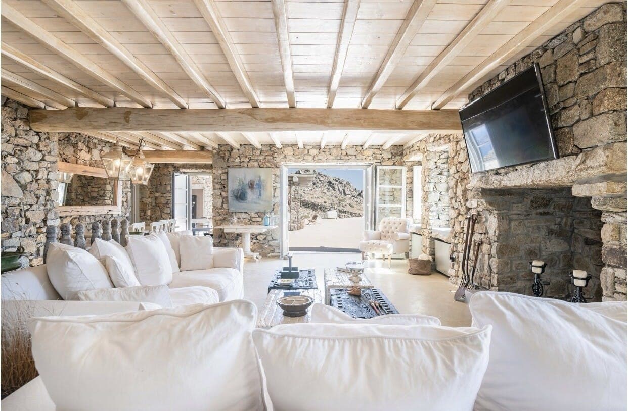 Stratos Views open-plan living room with stone walls and beamed ceiling, Mykonos, Greece
