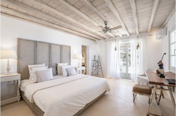 Stratos Views master bedroom with woven headboard and wood beams, Mykonos, Greece