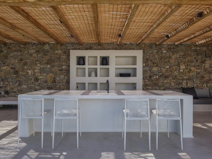 The Moon Muse outdoor dining terrace with stone walls, Agios Ioannis, Cyclades Islands, Greece
