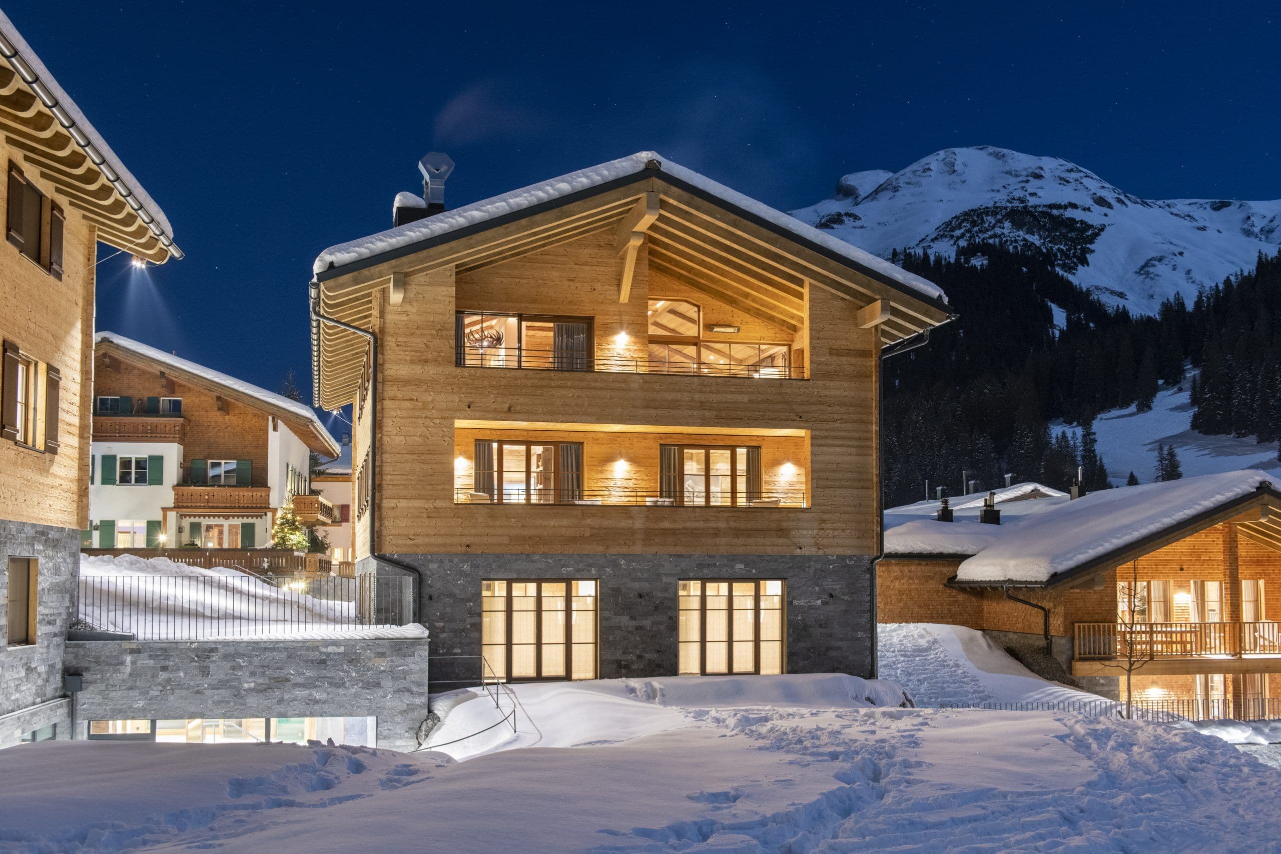 Chalech S illuminated chalet exterior at night with snow-covered mountains, Lech, Austrian Alps, Austria