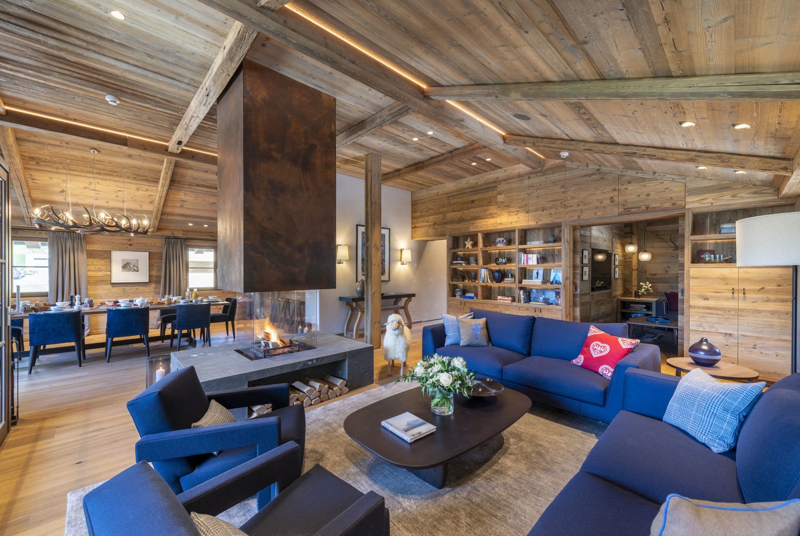 Chalech S open-plan living room with suspended fireplace and blue velvet seating, Lech, Austria