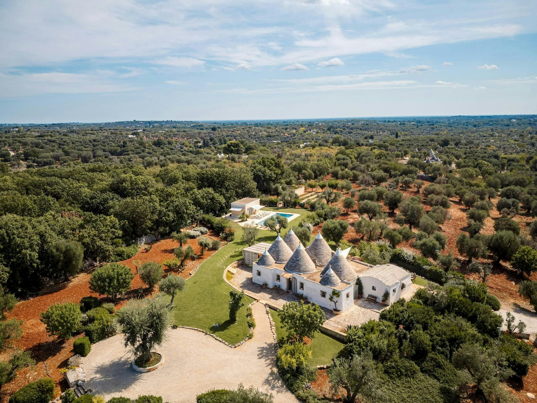White Village Escape aerial view of trullo villa in olive groves, Ostuni, Puglia, Italy