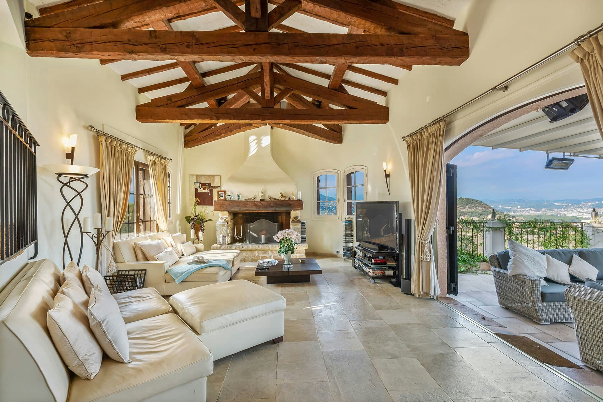 Villa Cactus living room with exposed beams and stone fireplace, Theoule-Sur-Mer, France